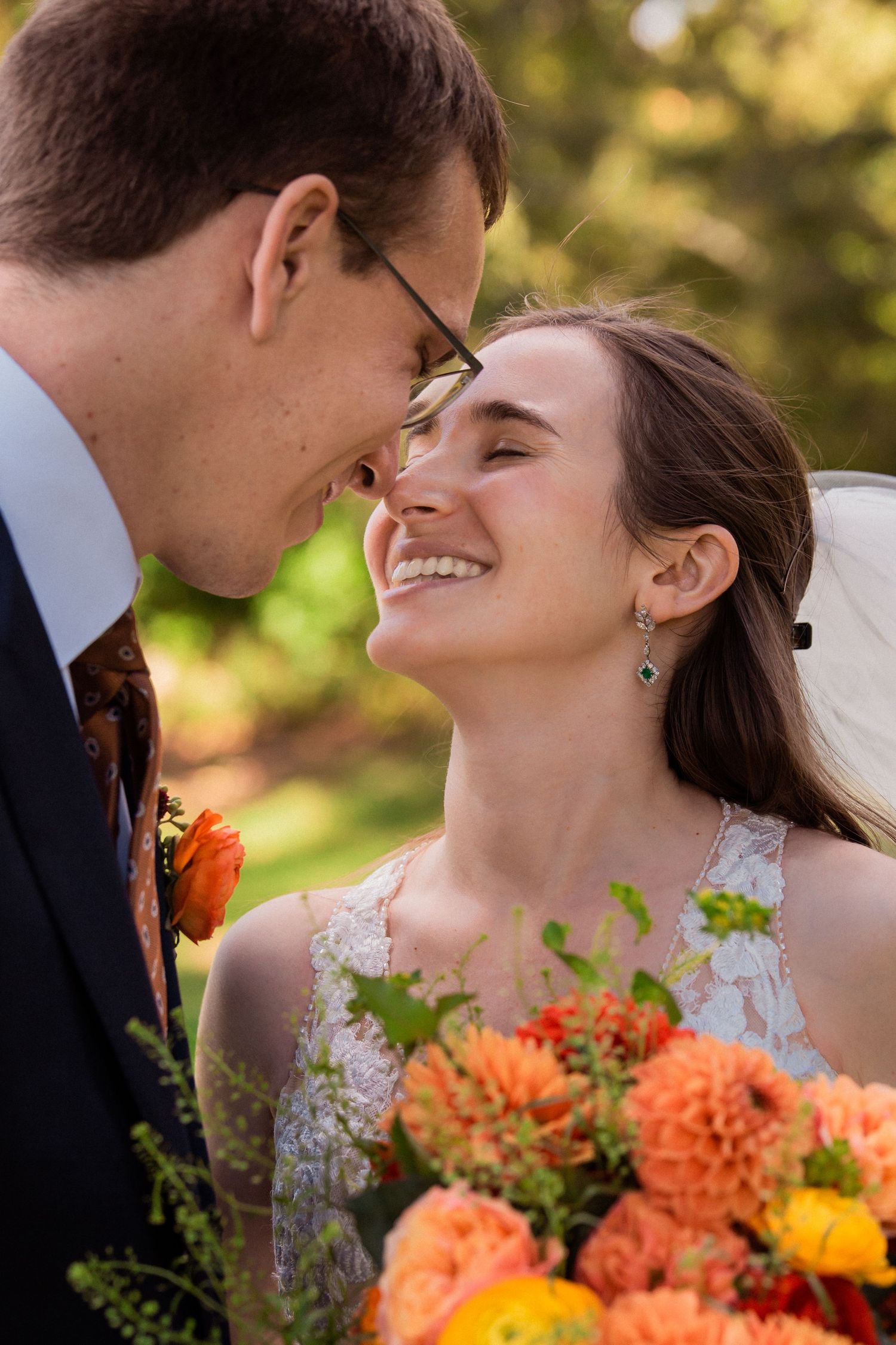Joyful bride and groom touching foreheads and smiling with vibrant orange floral bouquet outdoors, The Bradley Estate, Canton, MA