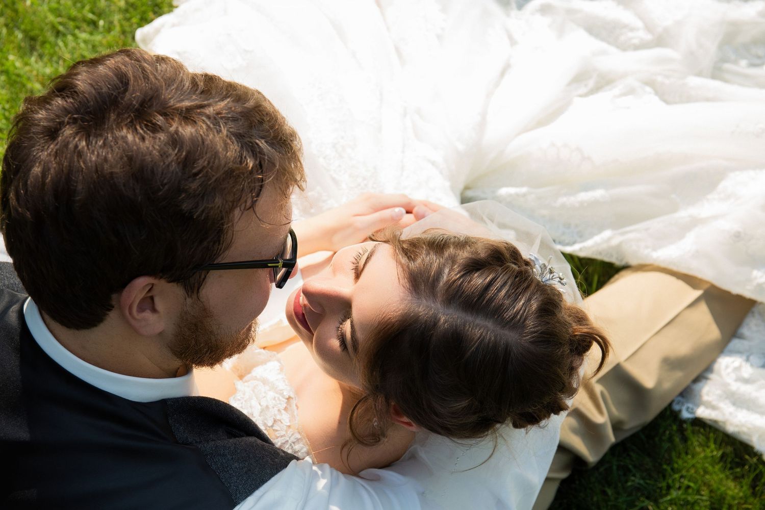 Bride and groom lying on grass sharing a romantic moment on their wedding day, Xenia Helix Photography, Boston, MA