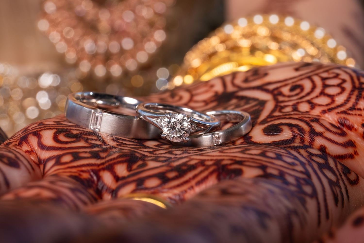 Close-up of wedding rings on henna-decorated hands with gold bangles, Xenia Helix Photography, Boston, MA