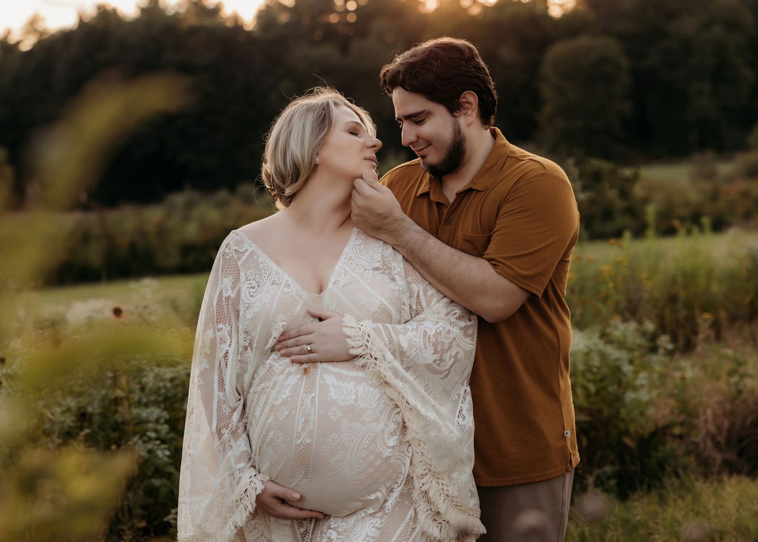 Xenia Helix and her husband sharing tender moment in golden sunset light in a wildflower meadow.