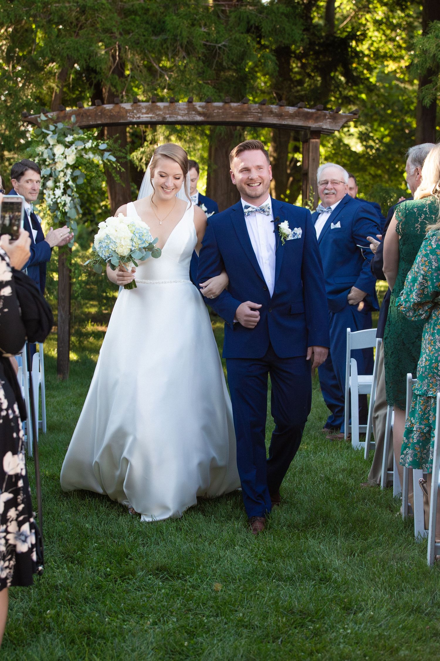 Happy newlyweds walking down outdoor aisle after wedding ceremony in lush garden, Stevens Estate at Osgood Hill, North Andover, MA