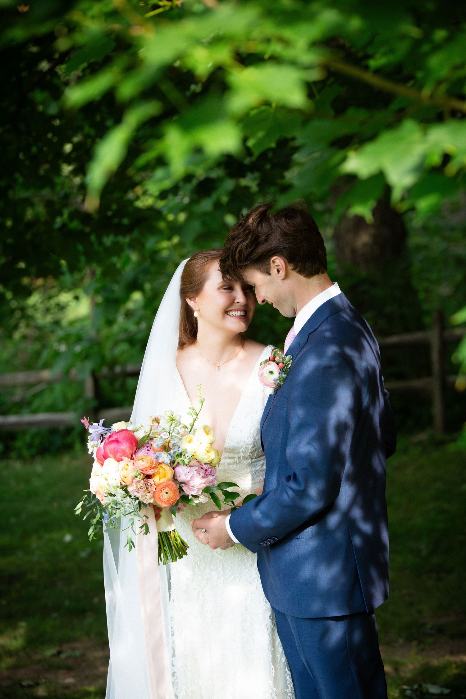 Bride and groom touching foreheads, bride holding colorful bouquet with veil, surrounded by lush trees, Grove at Briar Barn Inn, Rowley, MA