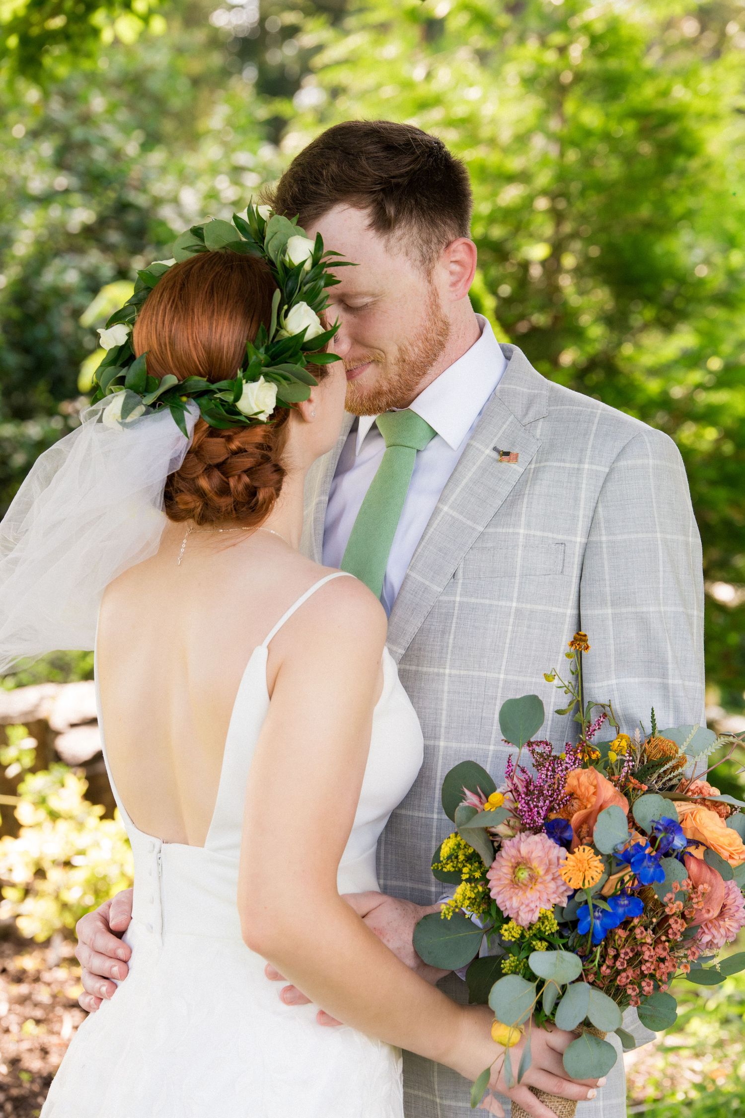 Bride and groom share a romantic kiss outdoors, bride wearing floral crown and holding colorful bouquet, Xenia Helix Photography, Boston, MA