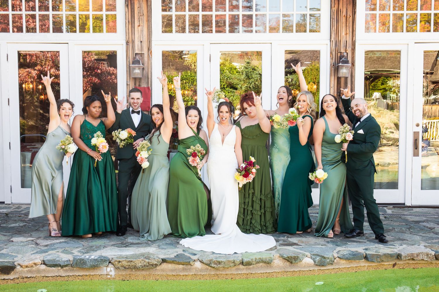 Bridal party celebrating in green gowns with bride in white gown outside rustic venue, The Red Lion Inn, Cohasset, MA