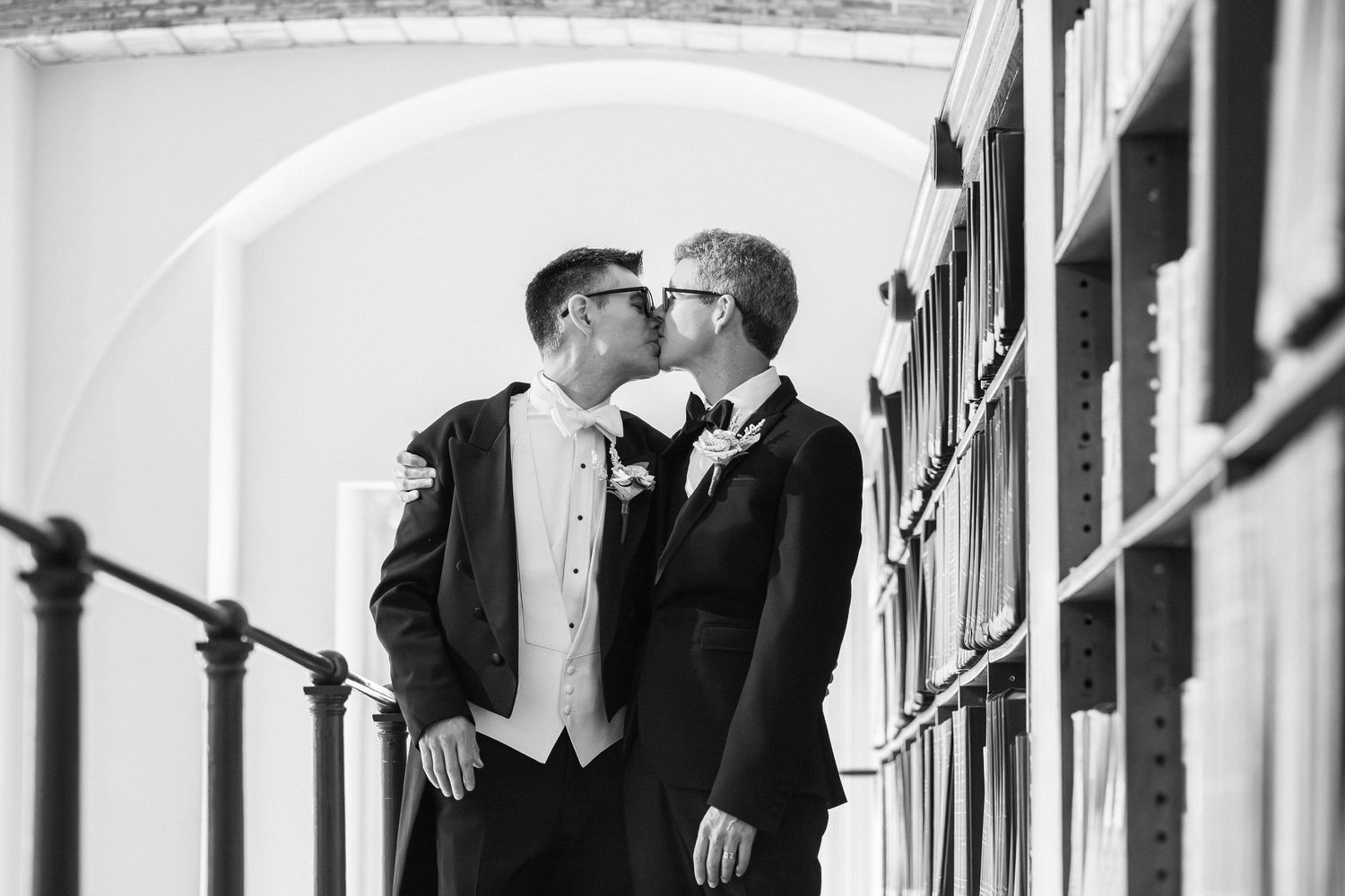 Two grooms share a romantic kiss in black and white photo at a Guastavino Room, Boston Public Library, Boston, MA