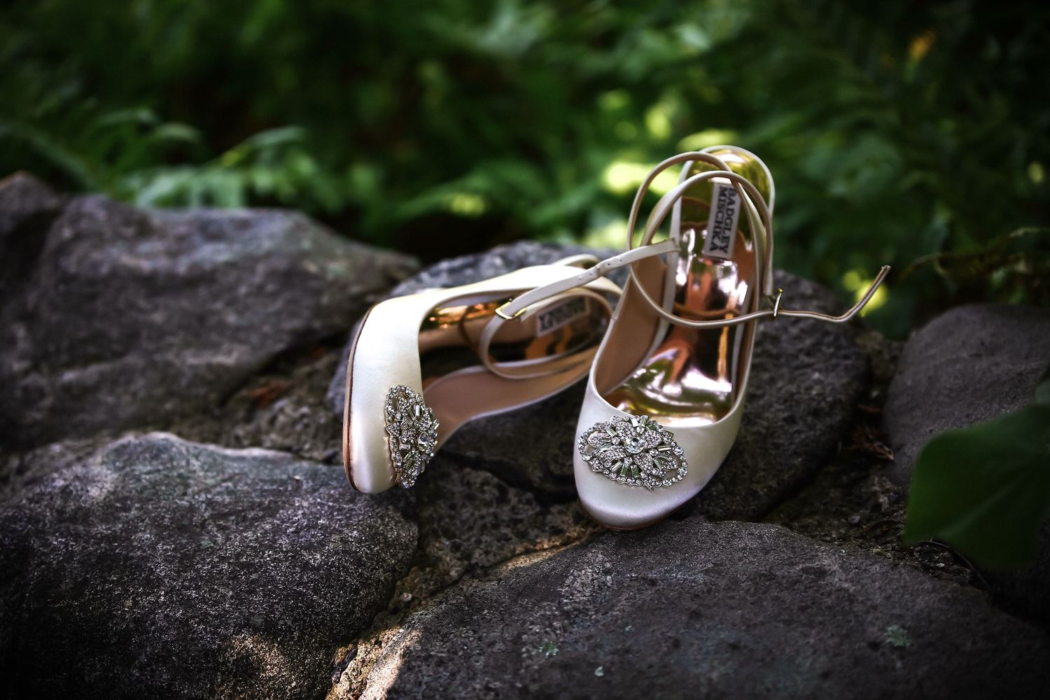 White bridal heels with crystal embellishments resting on mossy rocks in a lush garden setting, Mass Audubon's Habitat, Belmont, MA