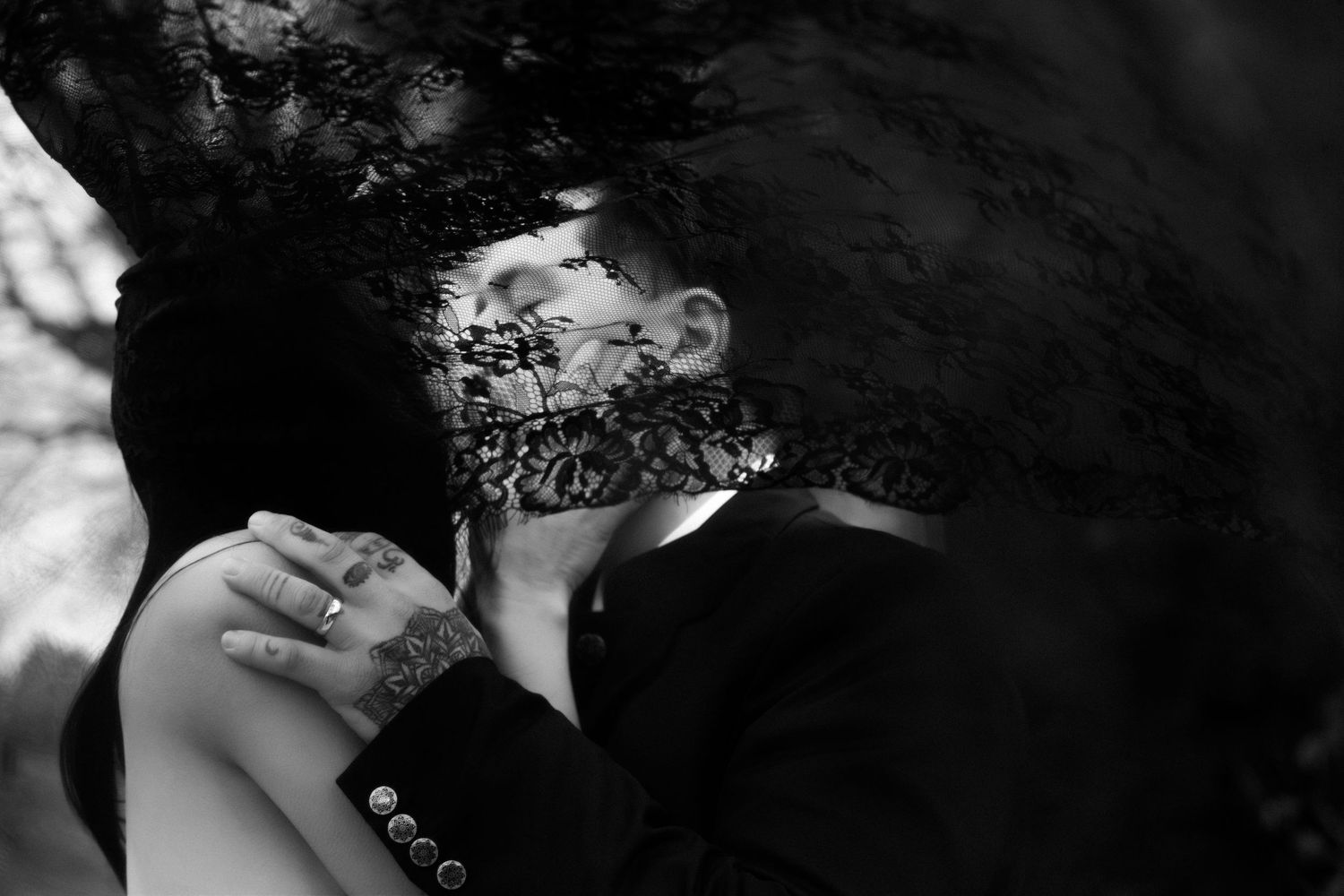 Black and white romantic photo of couple embracing under lace veil with groom's tattooed arm visible, The Chapel at West Parish, Andover, MA