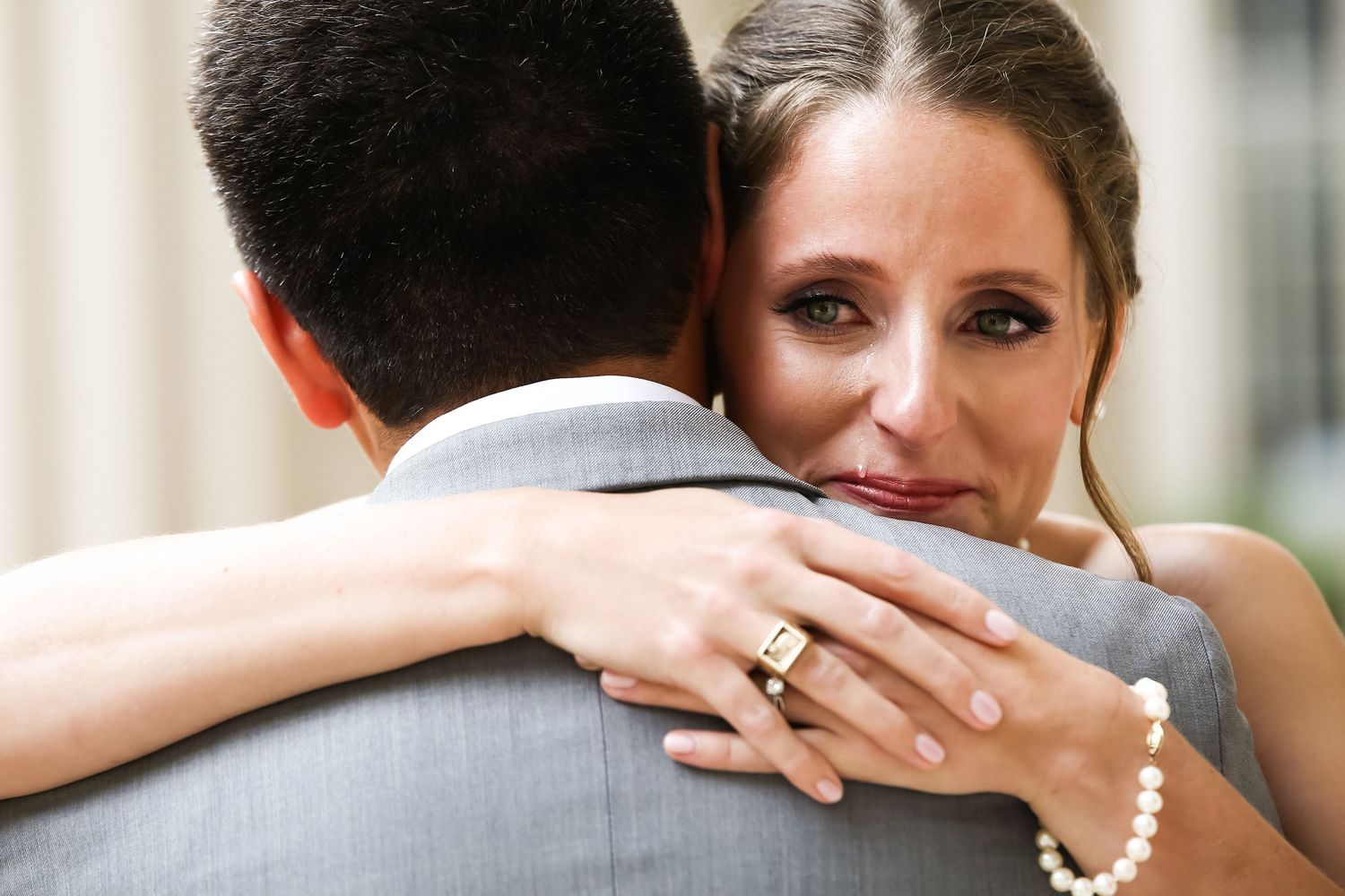 Emotional bride hugging groom, tears on her face, pearl bracelet and diamond ring visible during first look, MIT Great Dome, Cambridge, MA