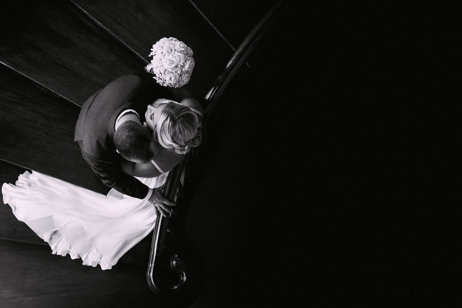 Aerial black and white view of bride and groom sharing a kiss on a staircase, Xenia Helix Photography, Boston, MA