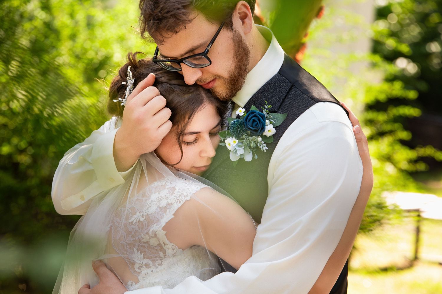 Couple sharing an intimate embrace in a garden, groom wearing a vest with a blue boutonniere, Xenia Helix Photography, Boston, MA