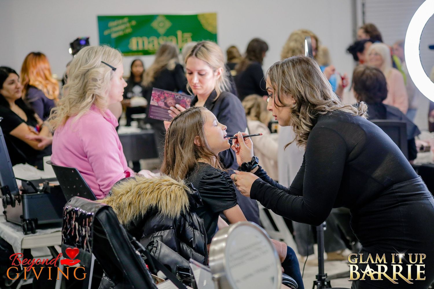 Multiple styling stations and vendors interacting with guests during the Glam It Up Barrie community empowerment event.
