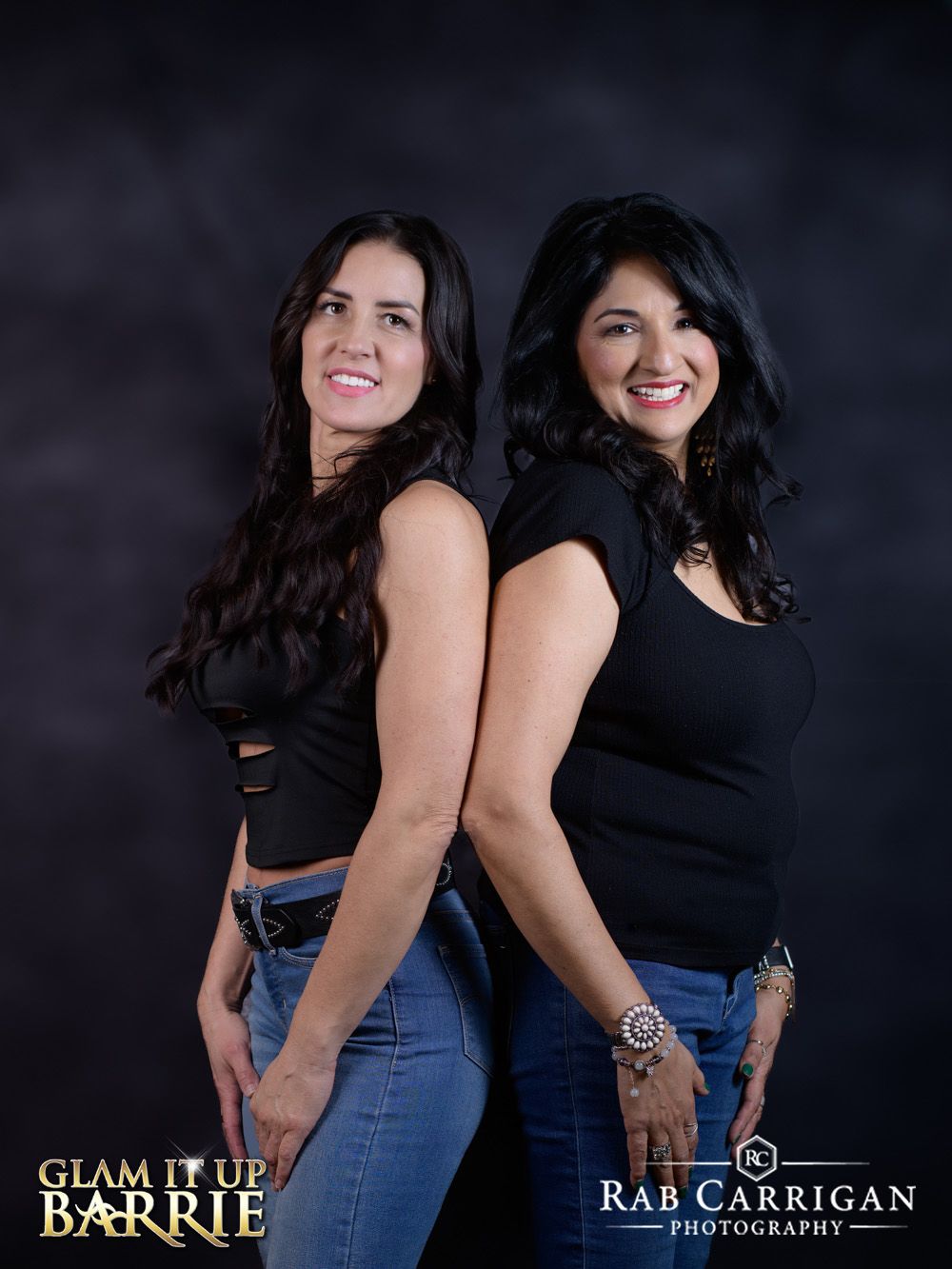 Two women standing back to back smiling during a professional portrait session at a local empowerment event.