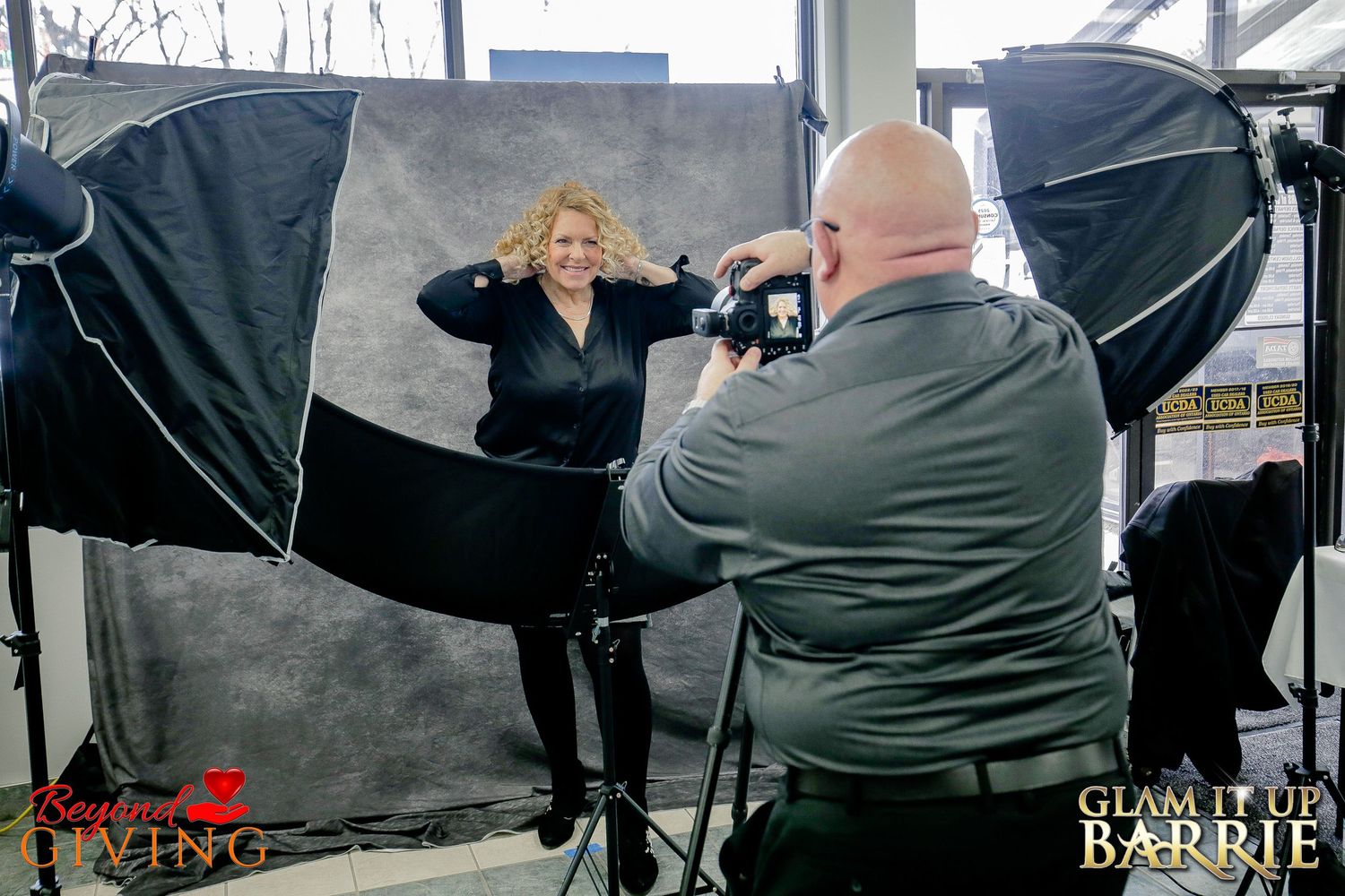 Professional photographer in a dedicated studio area at a Barrie fundraiser capturing a portrait of a smiling guest on a gray backdrop.