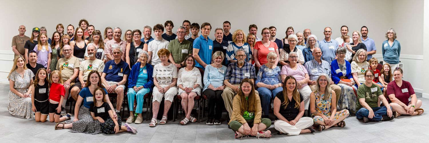 Large group photo of approximately 60 people posing together indoors for a group portrait.