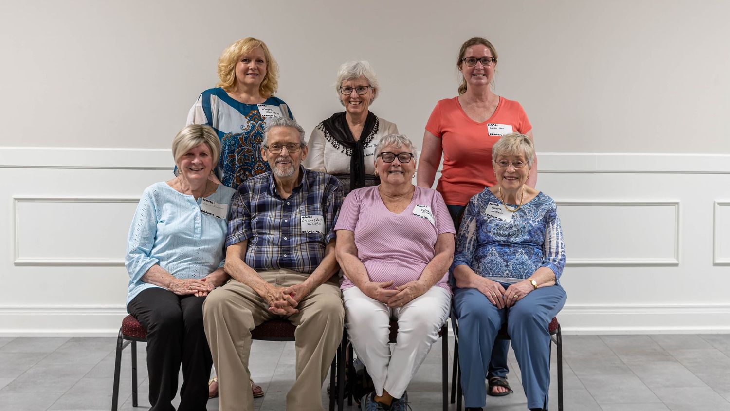 Group of eight seniors posing for a formal portrait, with four seated in front and four standing behind them.