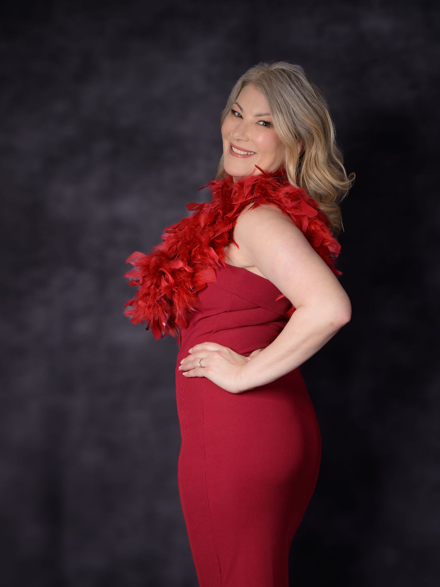 Blonde woman posing in red dress with feather boa in an elegant portrait photo.