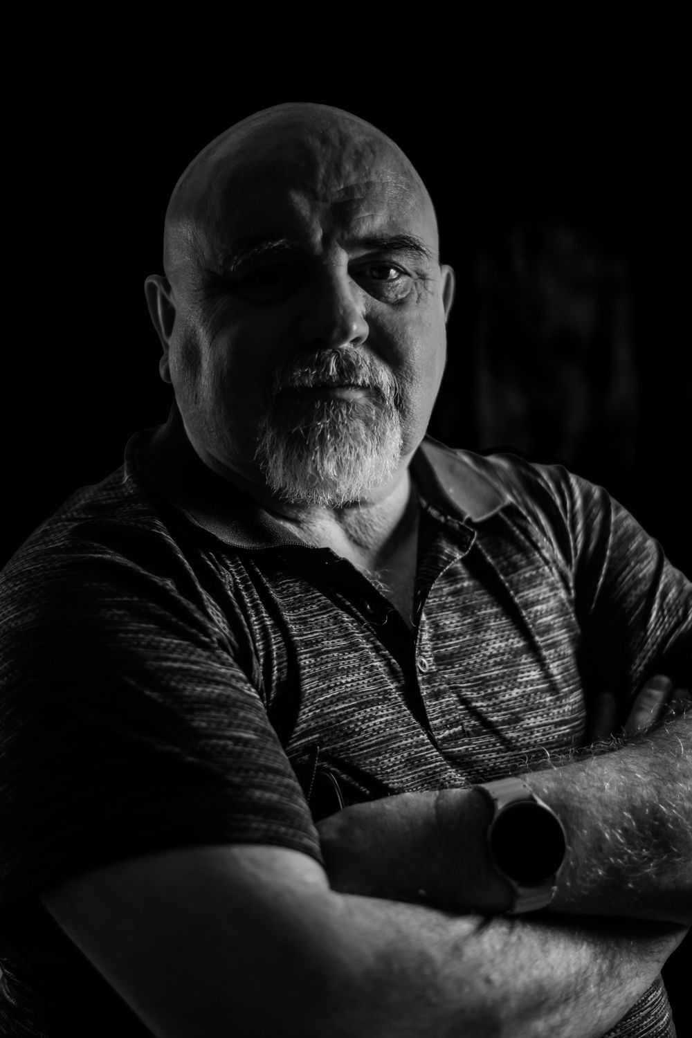 Dramatic black and white portrait of Rab Carrigan with high contrast lighting, highlighting facial contours against a dark background.