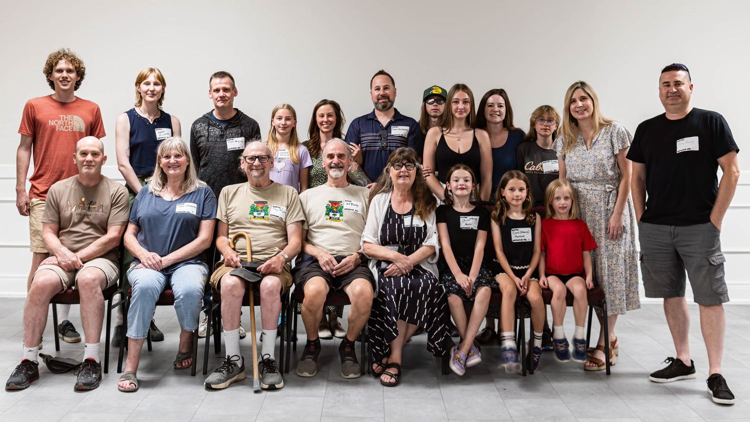 Large group of adults and children posing together for a family or community portrait in a bright indoor setting.
