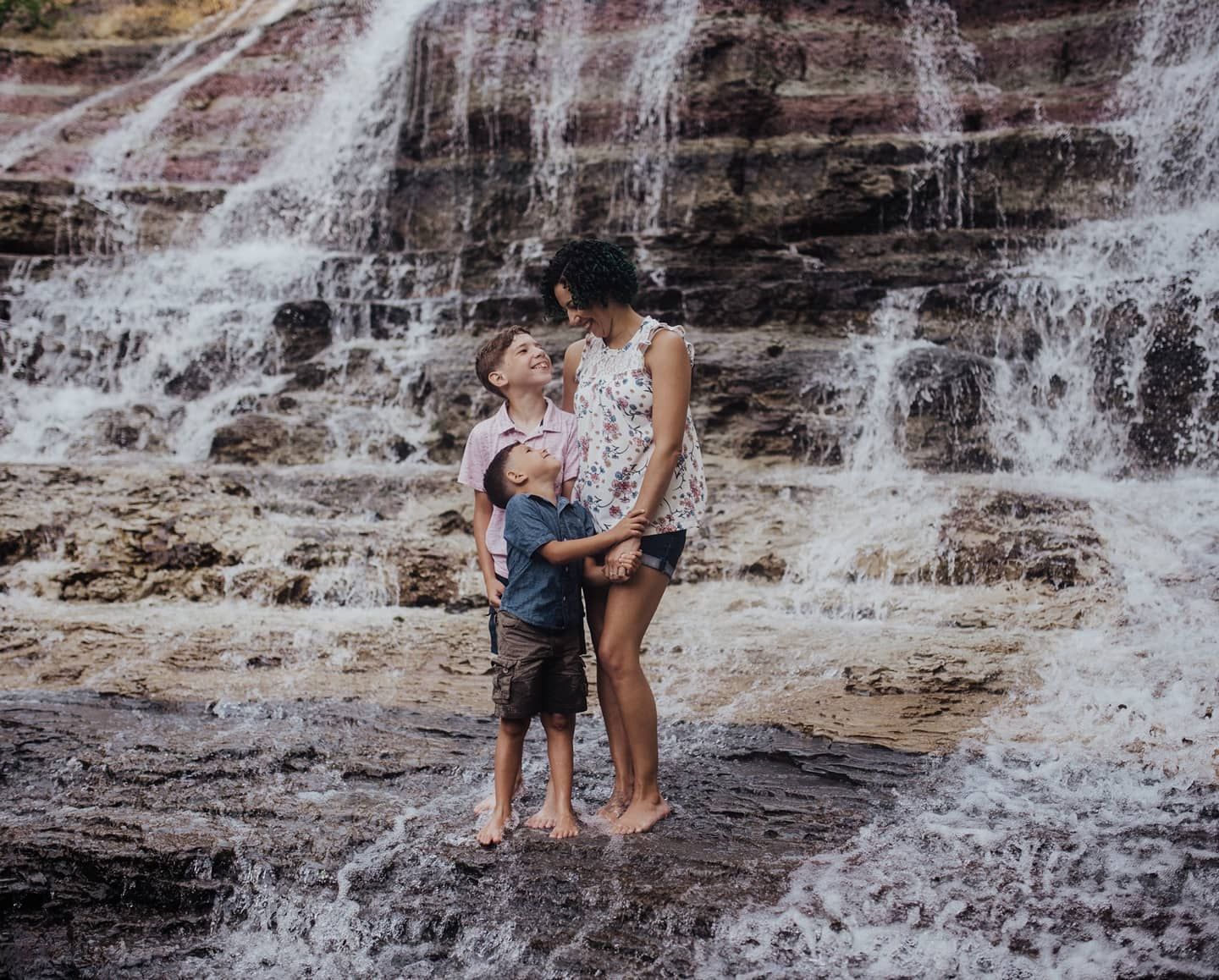 A family shares an intimate moment together at a cascading waterfall.