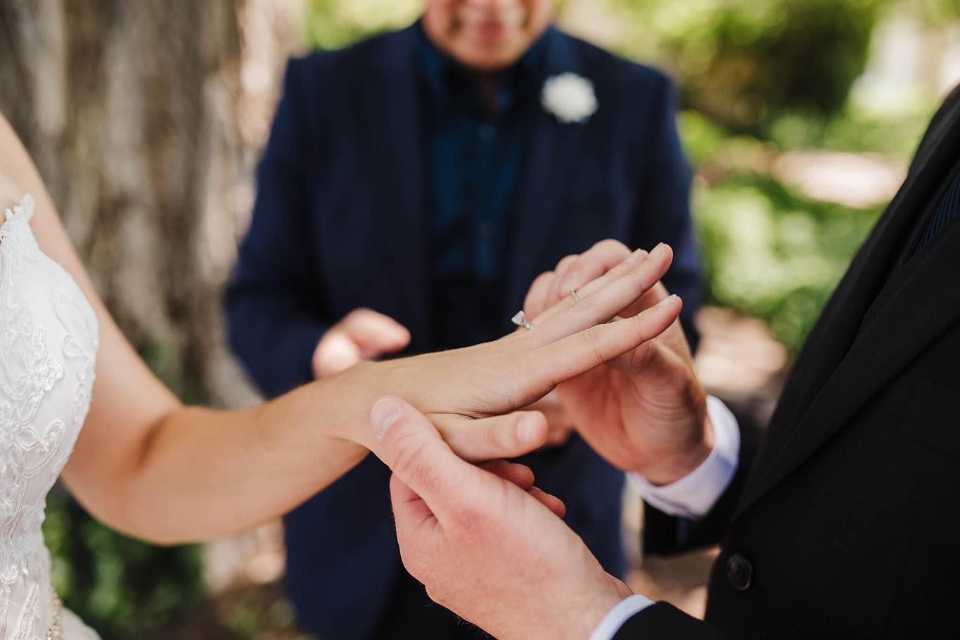 Close-up of couple holding hands during outdoor wedding ceremony.