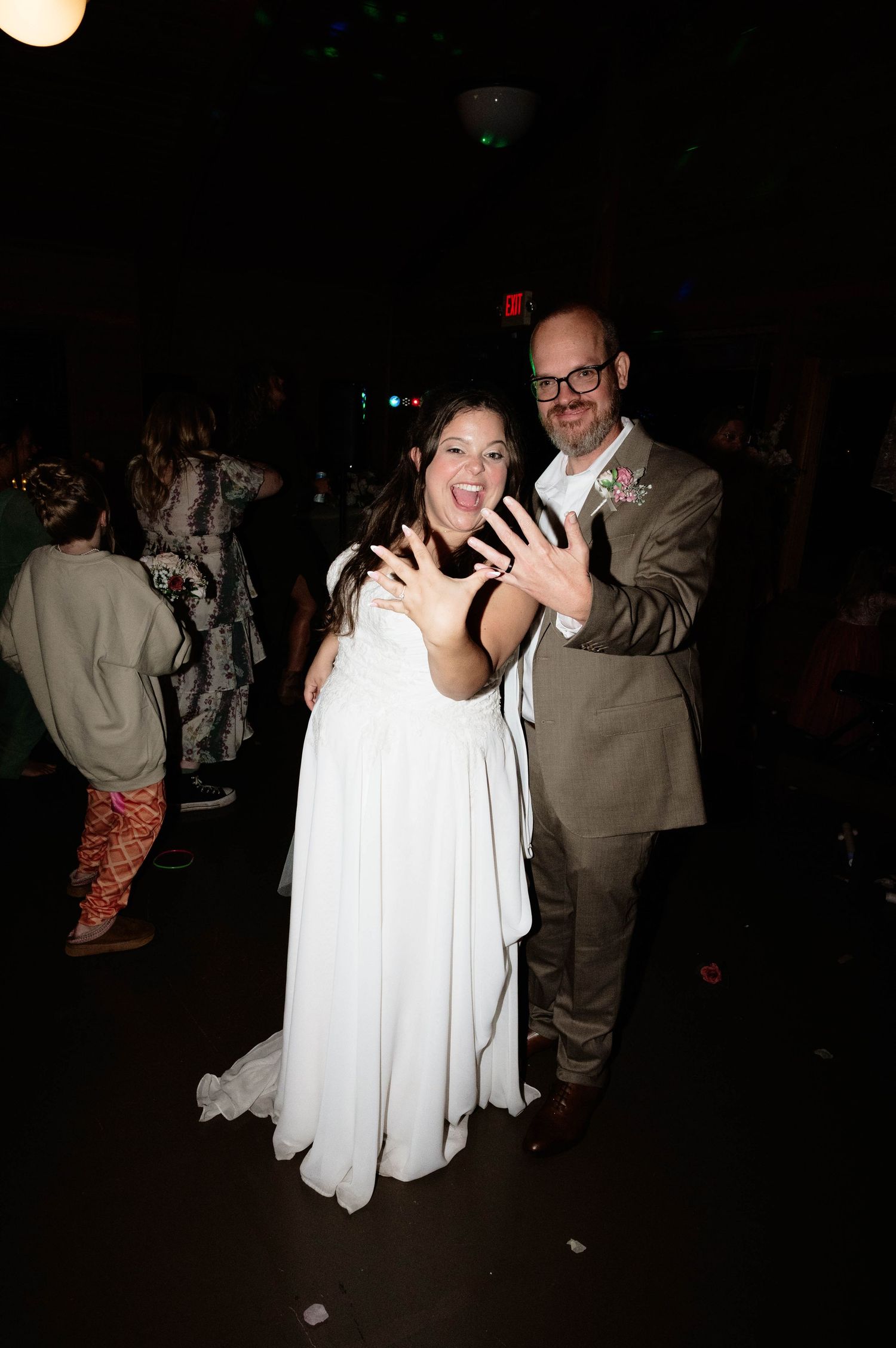 Wedding reception dance party with couples dancing in dim lighting.