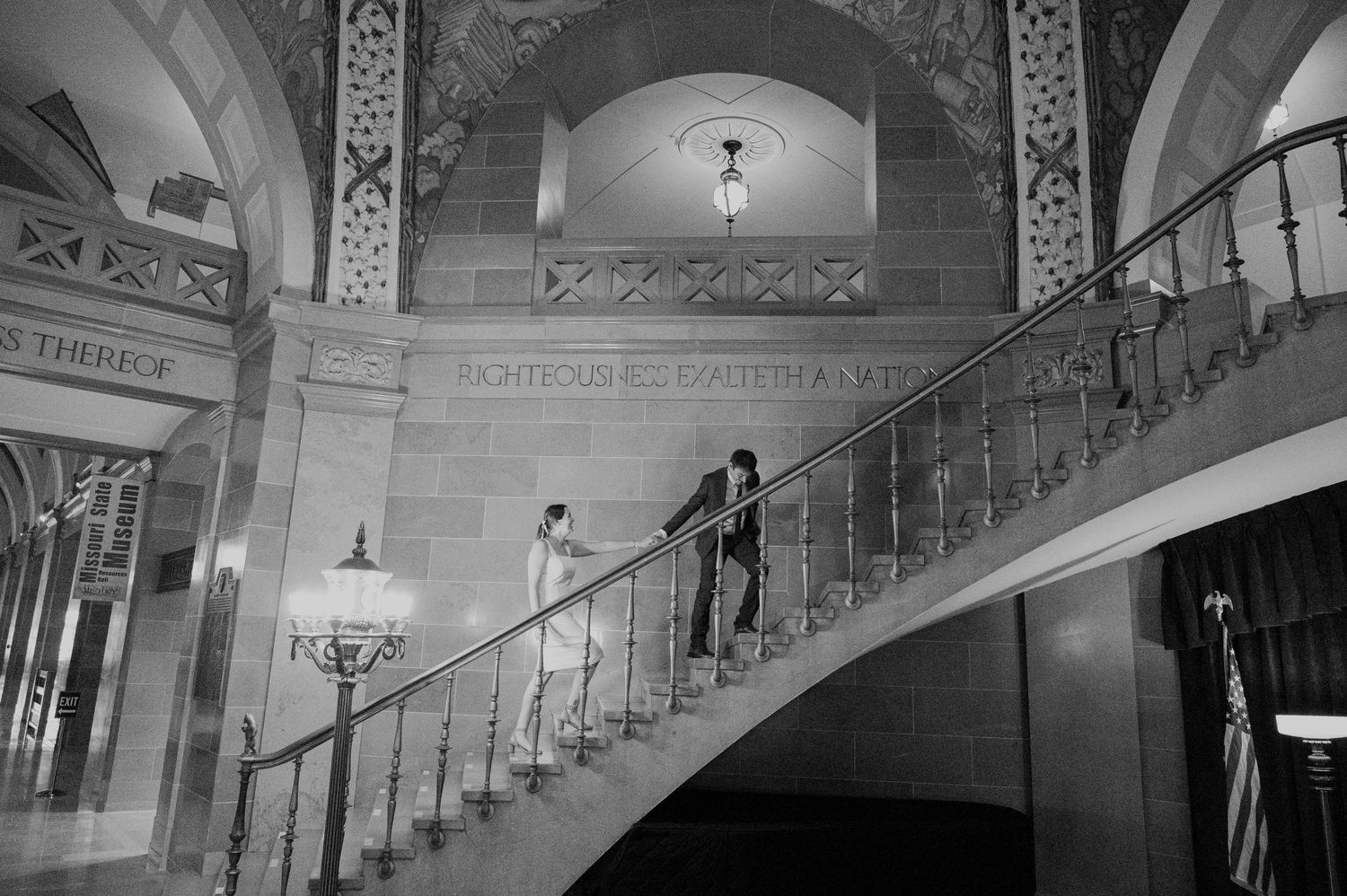 A couple poses on an elegant vintage staircase in black and white.