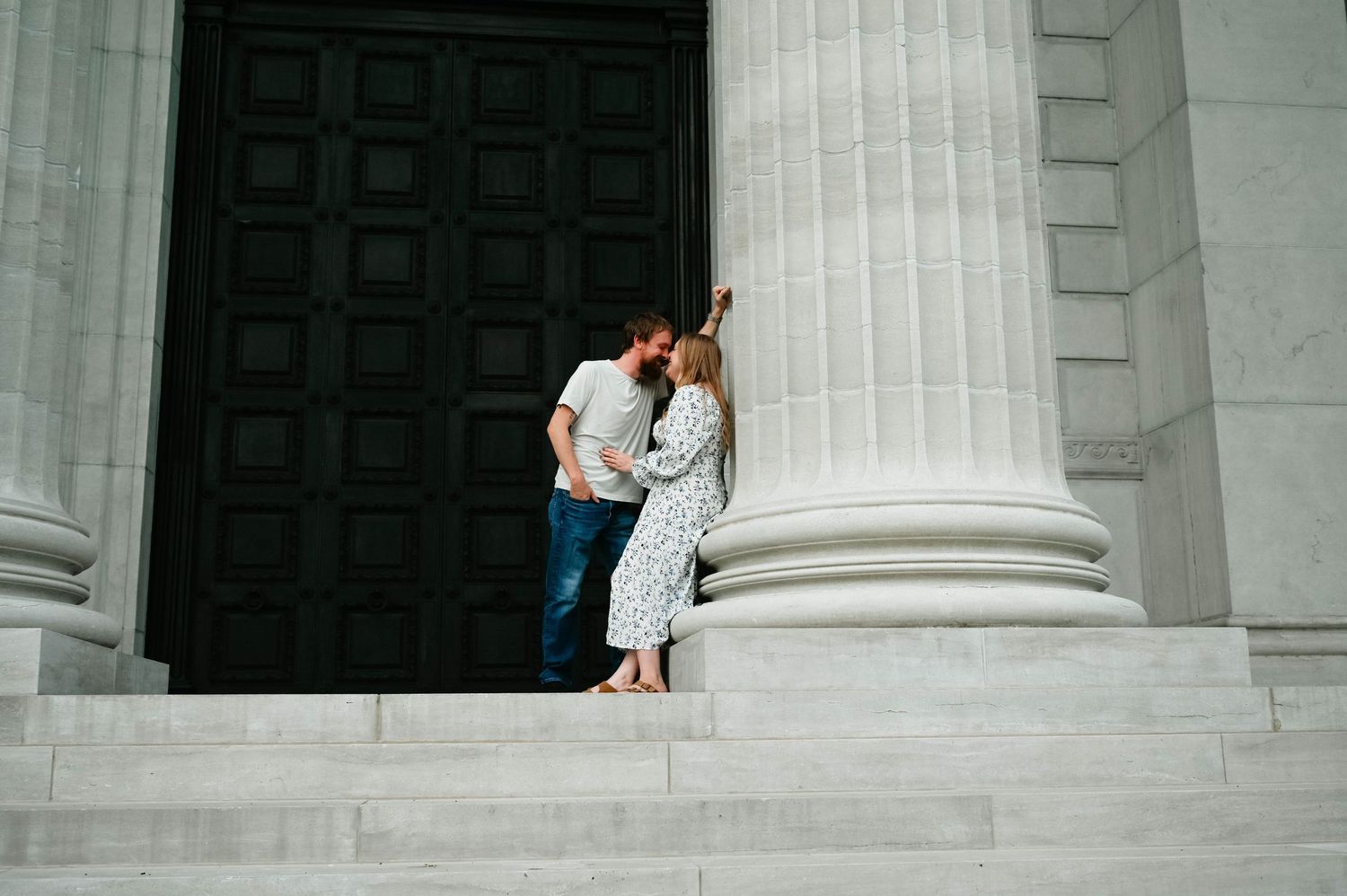 A tender moment between a couple against white columns of a classical building.