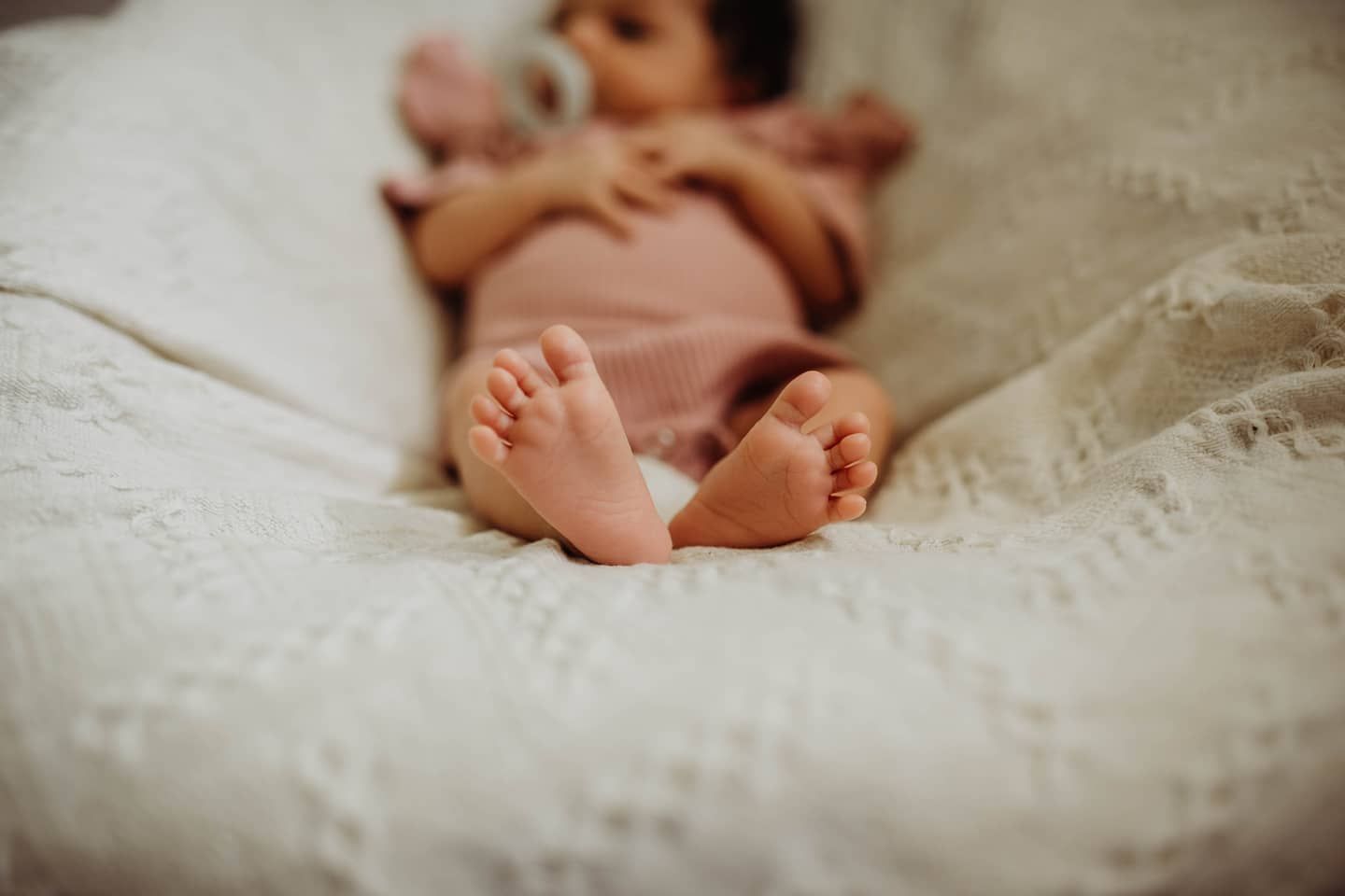 Series of peaceful sleeping newborn detail shots on white textured fabric.