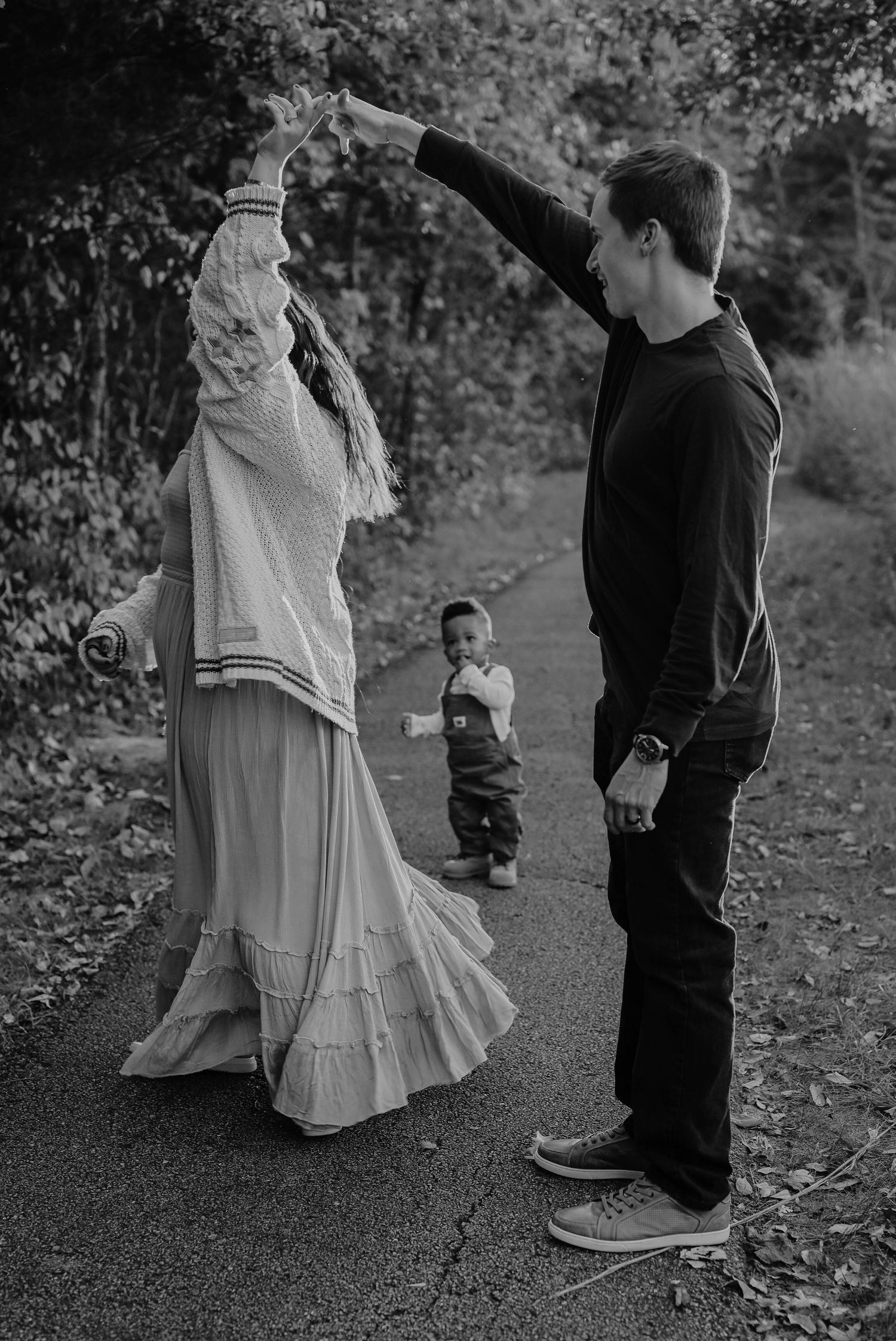 A family dances together on a path surrounded by autumn foliage.