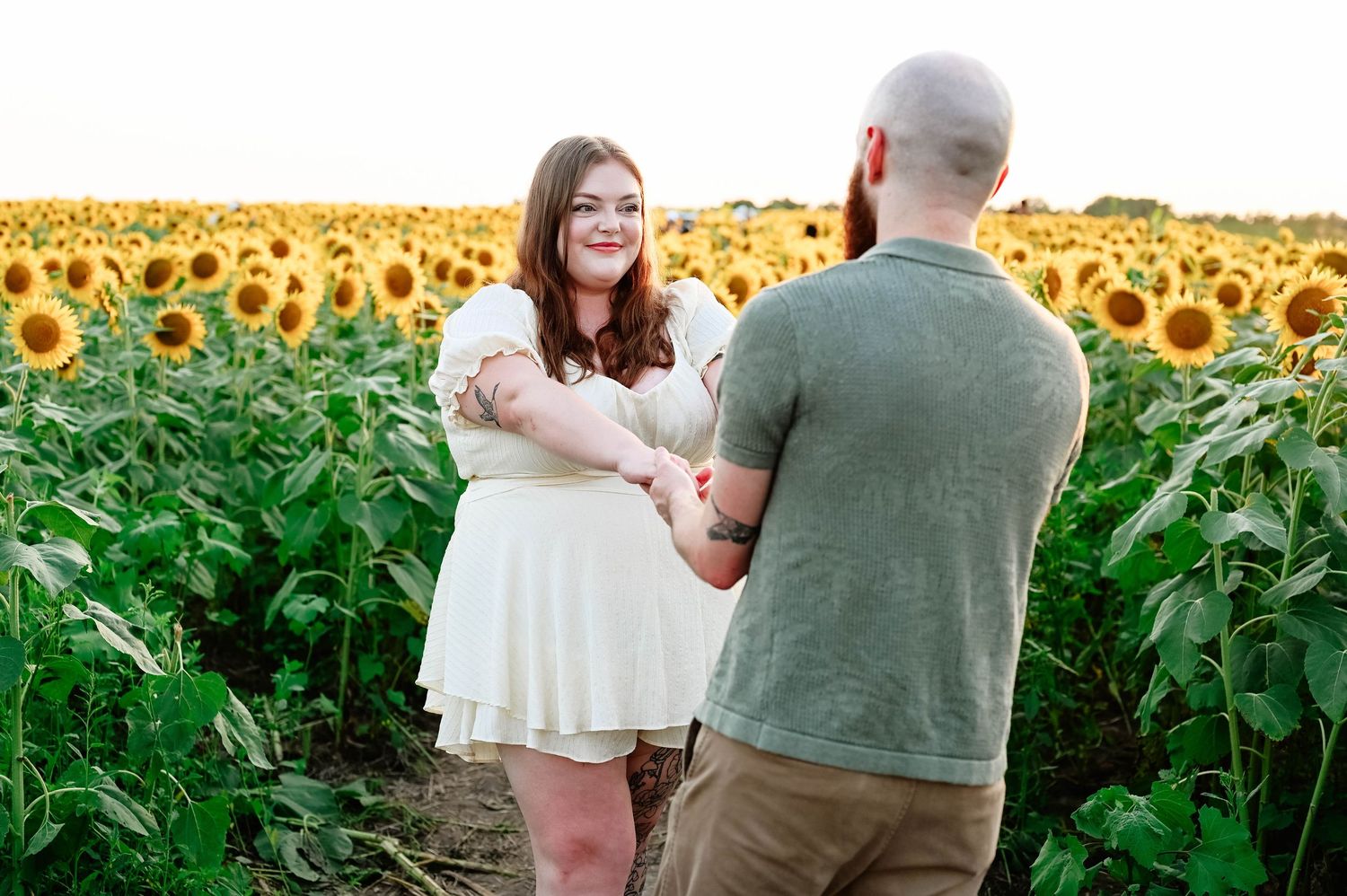 A couple shares an intimate moment in a vibrant sunflower field.