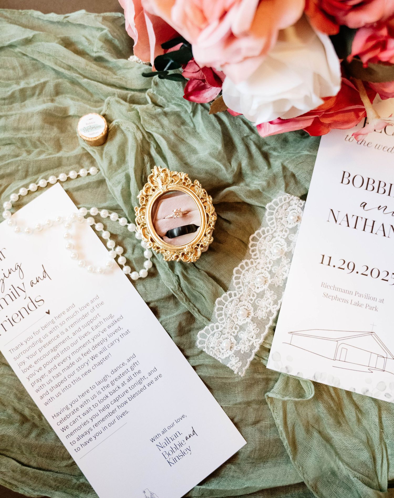 Wedding invitation suite with floral details and delicate lace on sage green fabric.