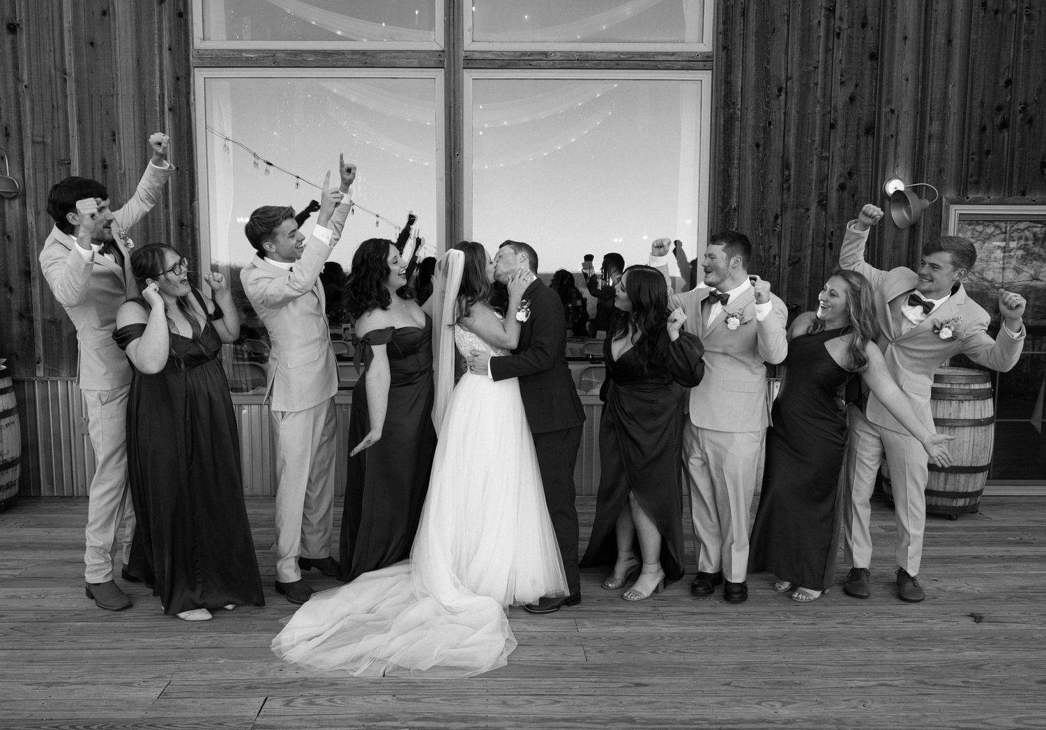 Black and white sequence of wedding party celebration and dancing in rustic venue.