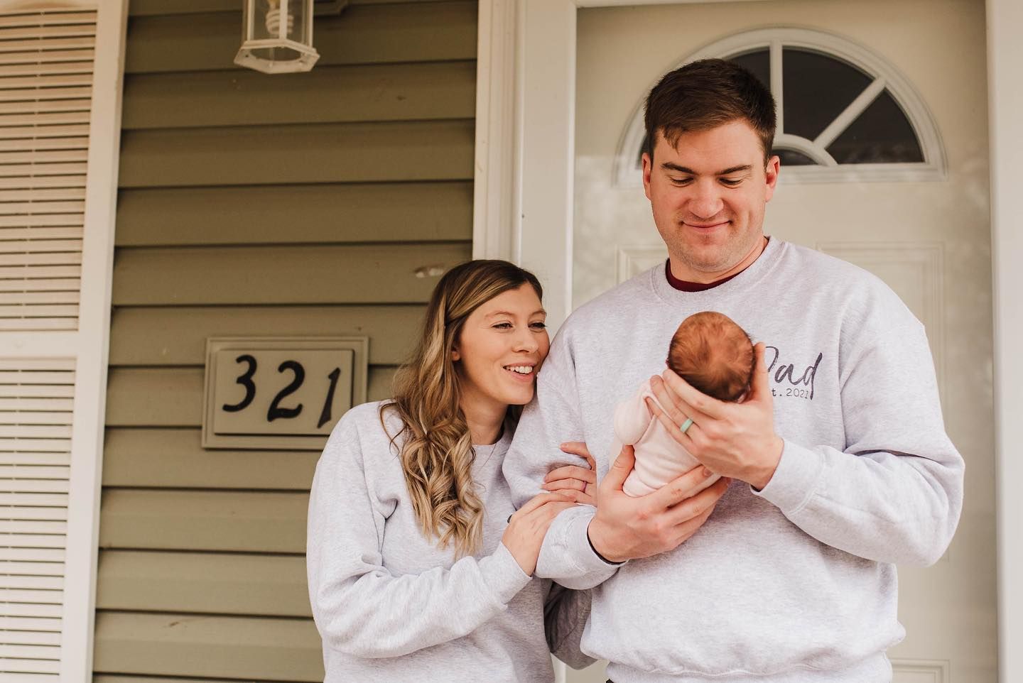 Family photoshoot in matching white outfits on front porch of house.