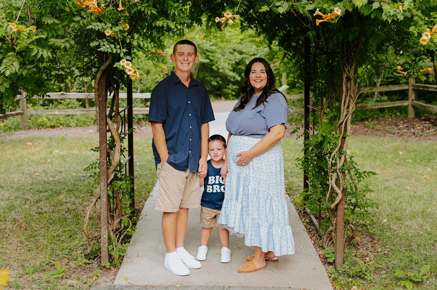 Family poses for portraits in a lush garden setting with green foliage.