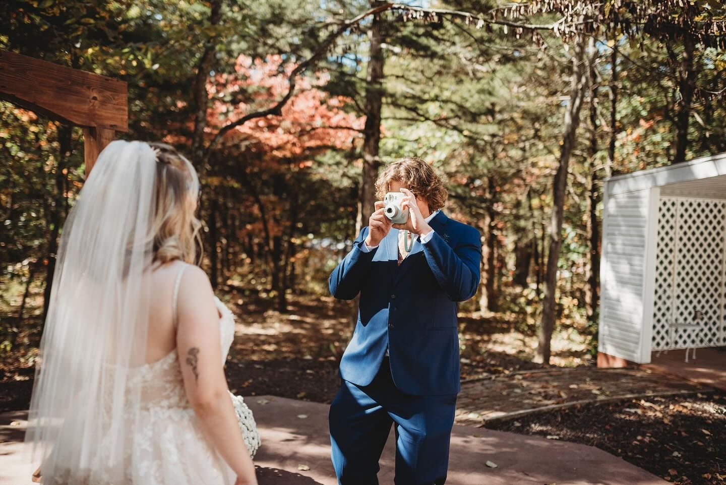 Couple shares first look moment in a wooded outdoor setting.