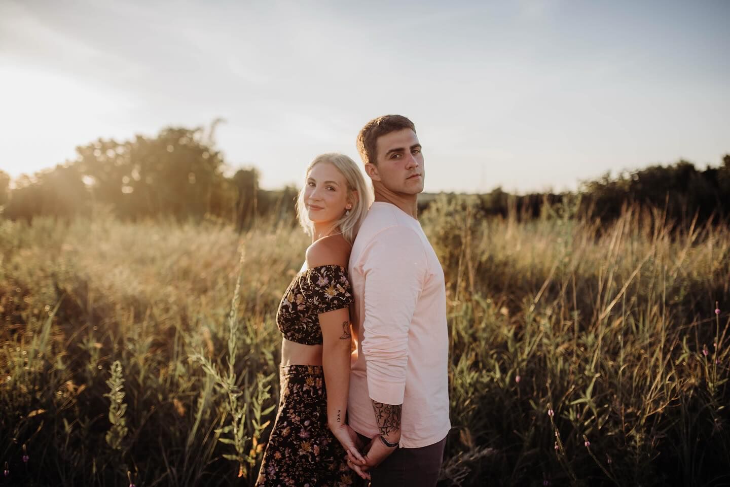Romantic sunset photoshoot in a golden field with tall grass and warm lighting.