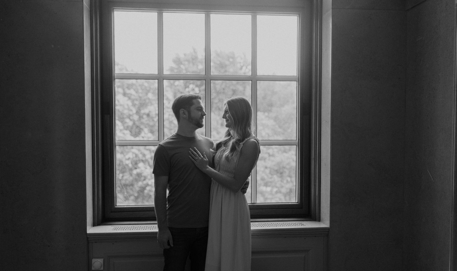 Silhouettes by a large window in black and white photography.