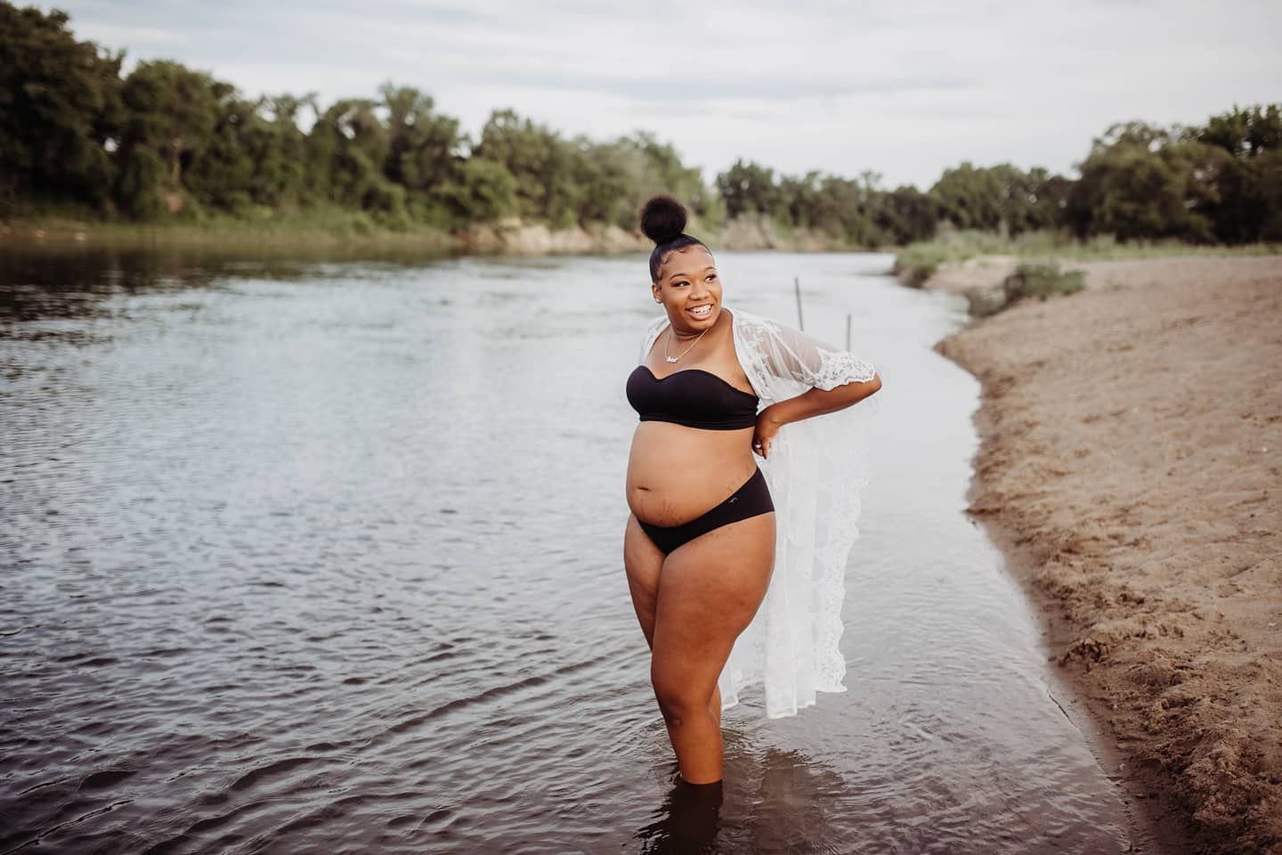 Natural waterfront landscape with a figure standing at the water's edge.