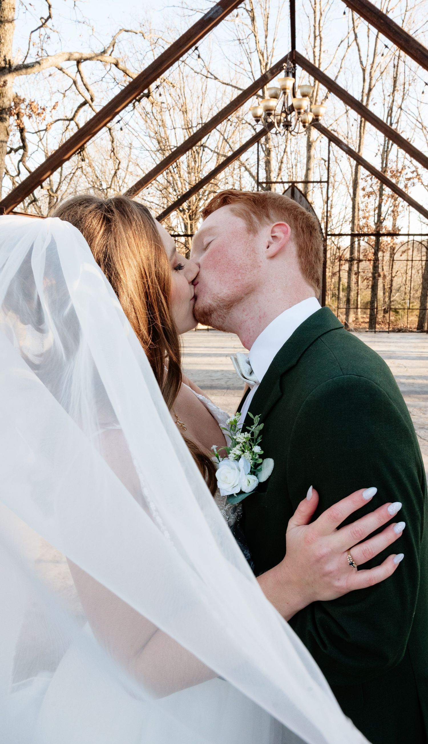 Romantic wedding kiss sequence with flowing veil against winter backdrop.
