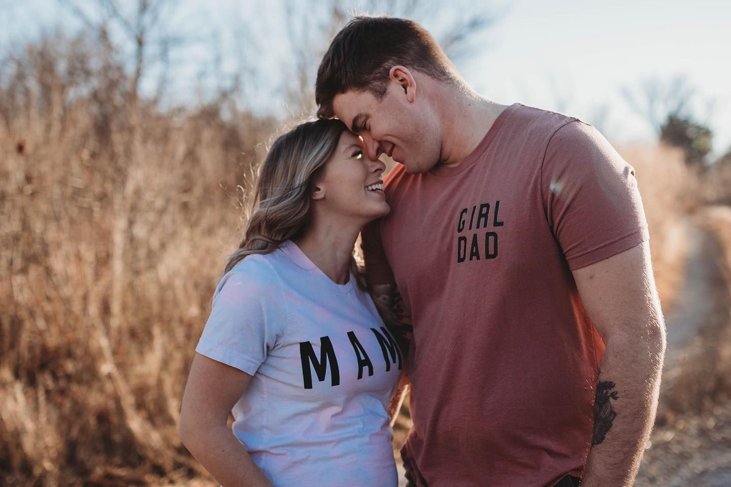 Romantic couple embracing in a golden sunset field with tall grass.