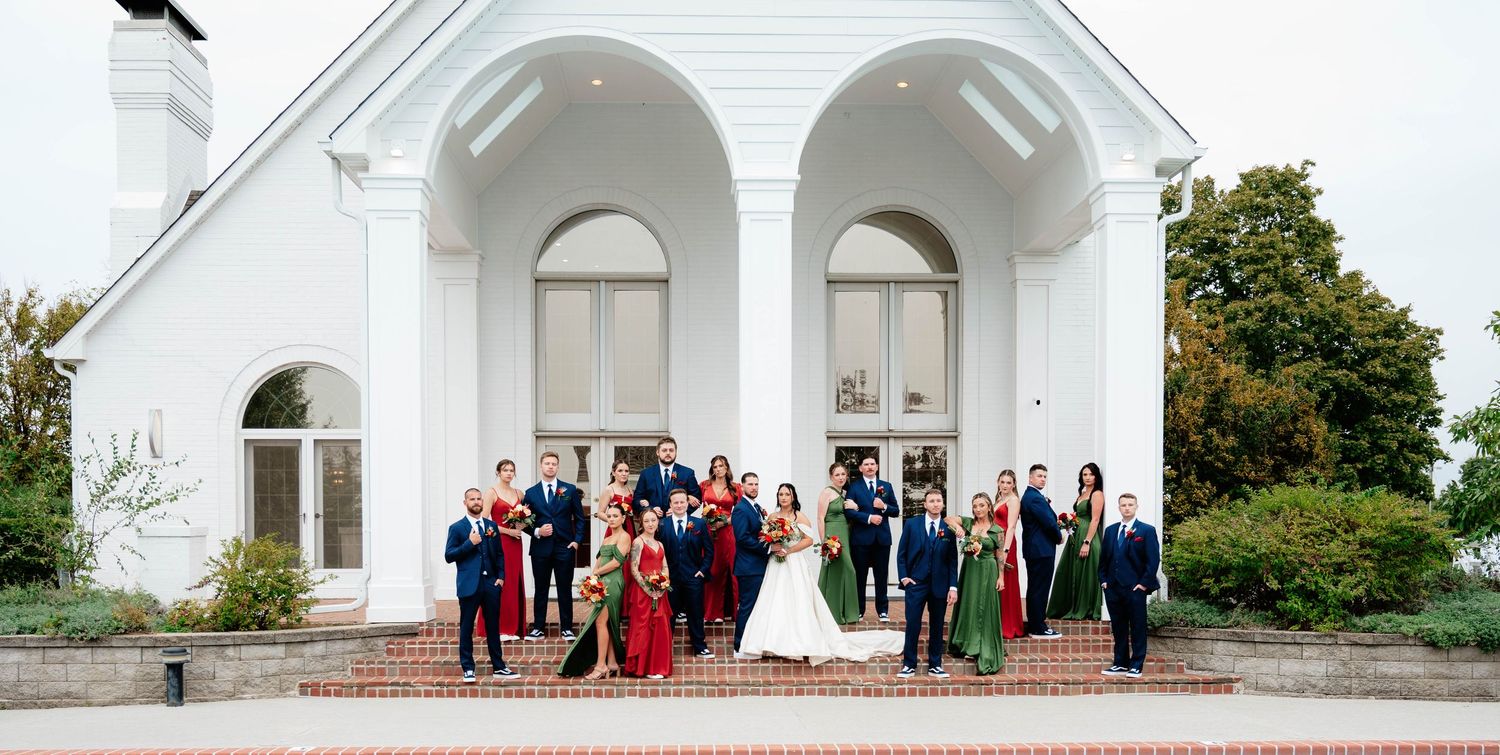 Elegant white church exterior with wedding party gathered outside.