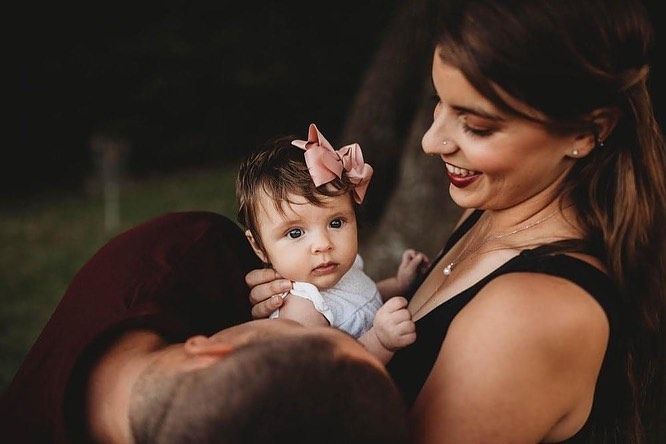 A tender moment between parent and baby with a pink bow in soft lighting.