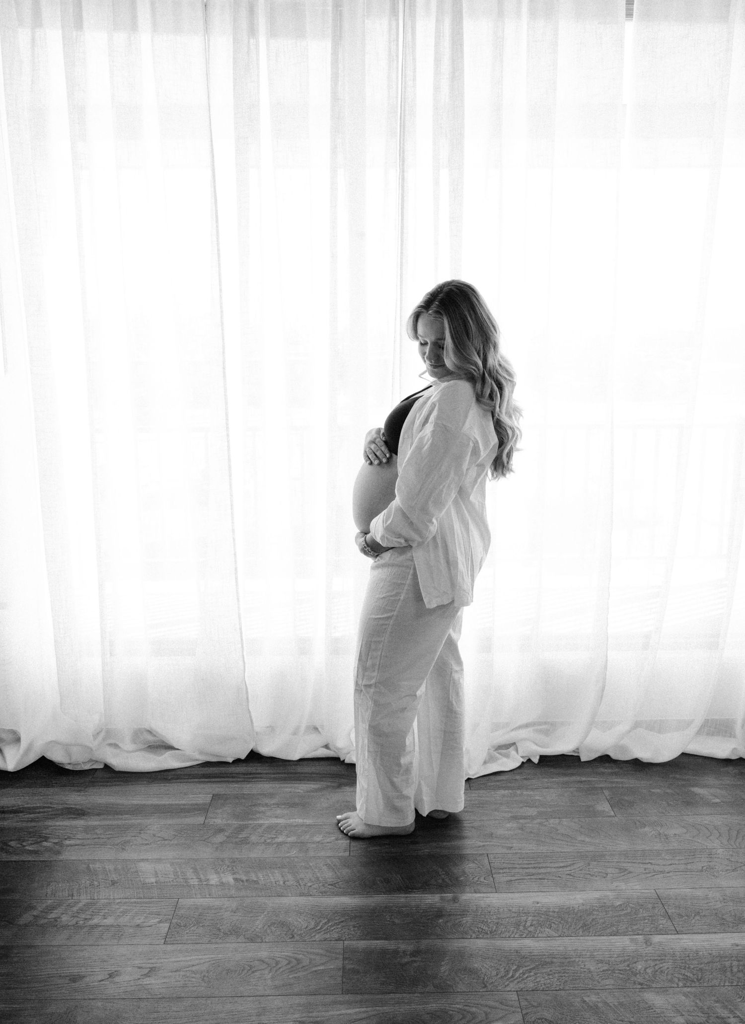 Black and white maternity portraits showing silhouette against white curtained window.