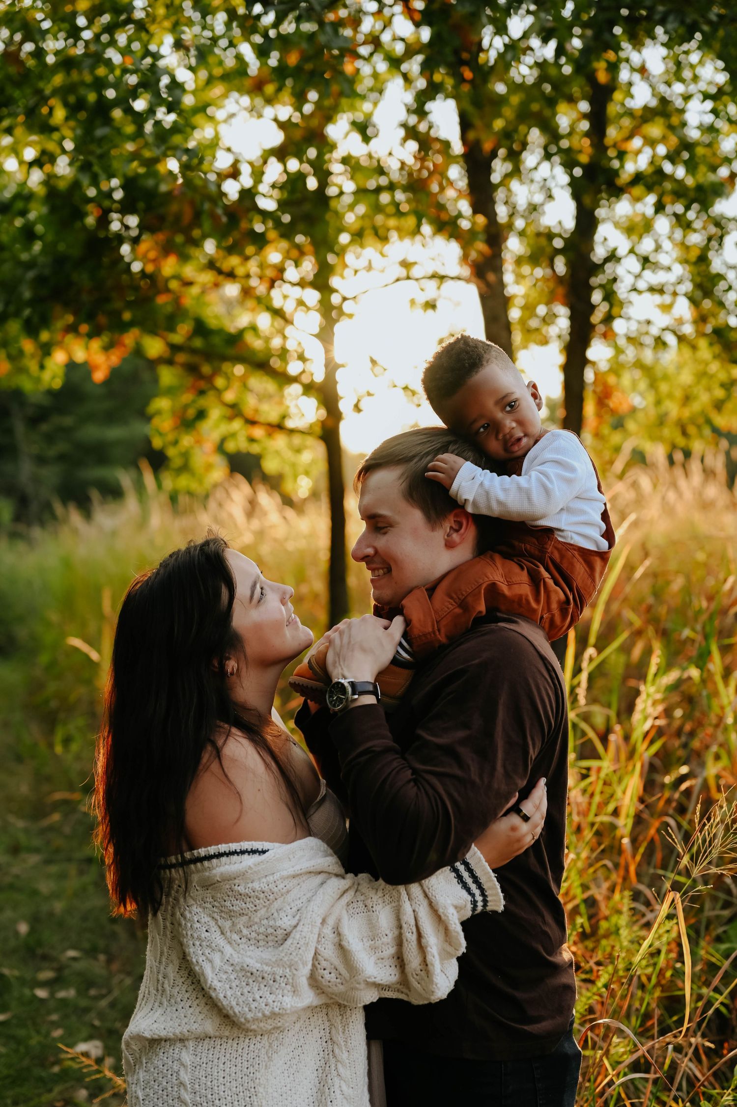 Family shares joyful moments together in golden autumn sunlight among trees.