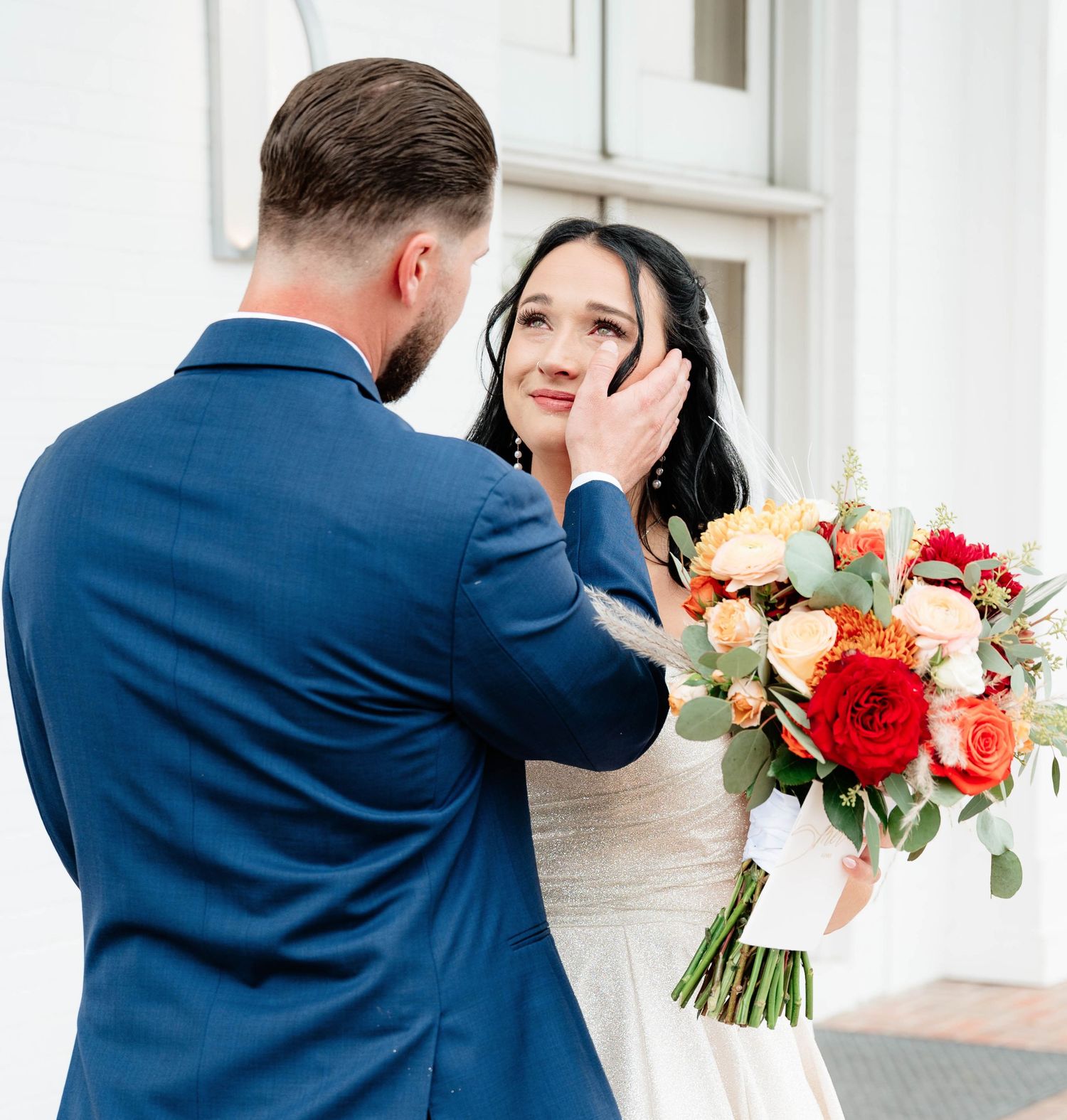 Romantic first look moment with couple holding vibrant floral bouquet.