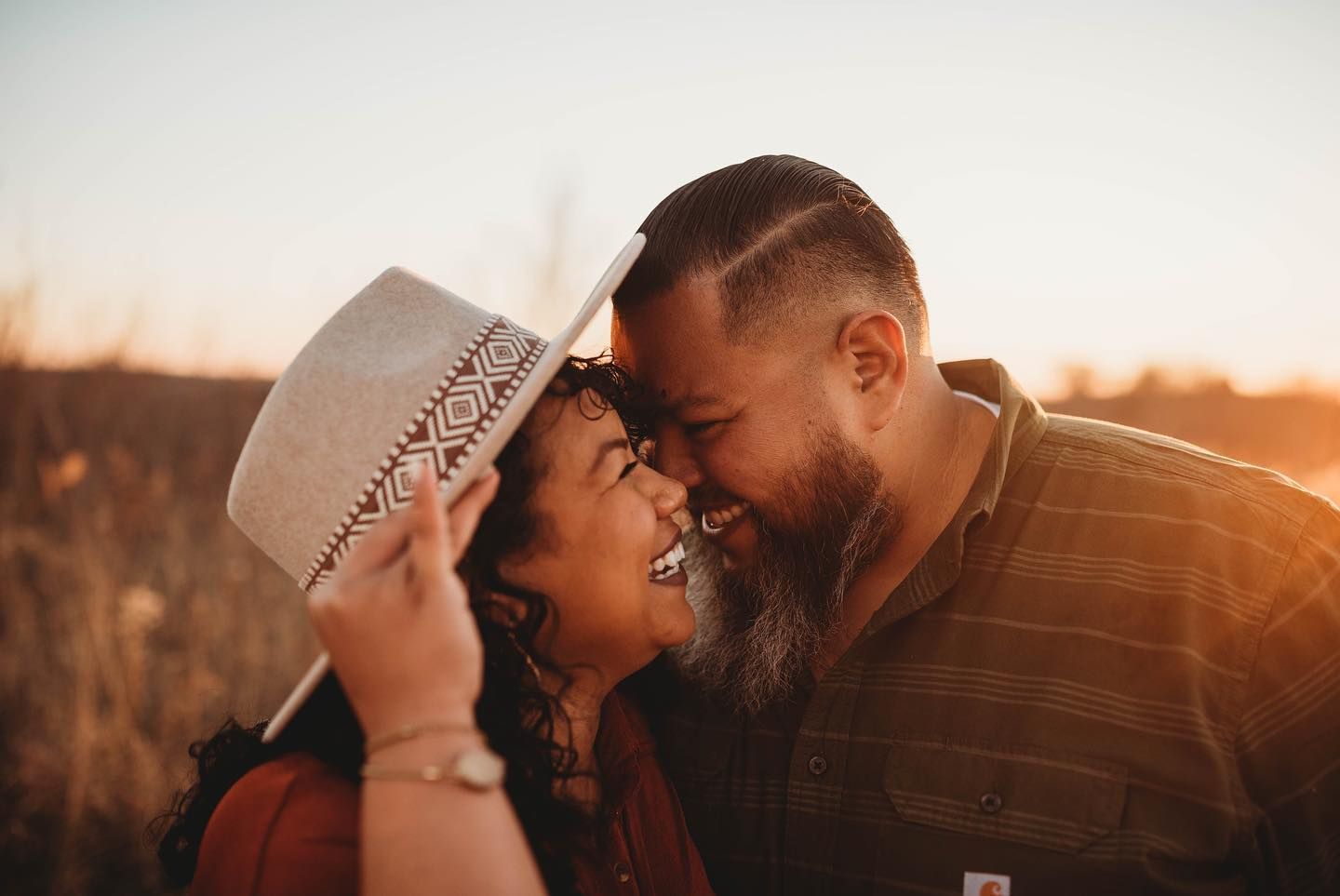 Intimate sunset portraits with cowboy hats creating silhouettes against warm sky.