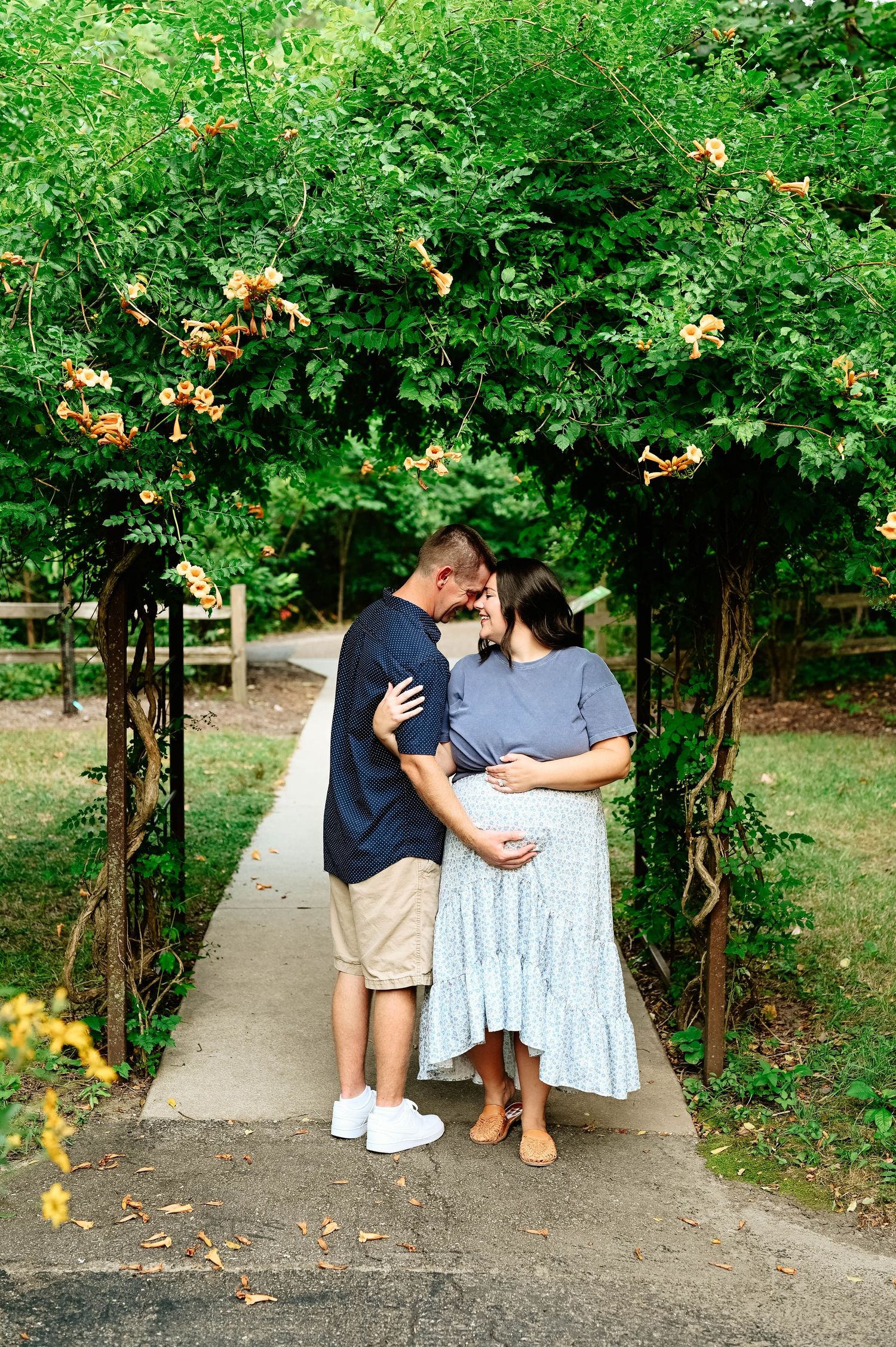Garden path photoshoot with yellow flowers and green foliage creating natural archway.