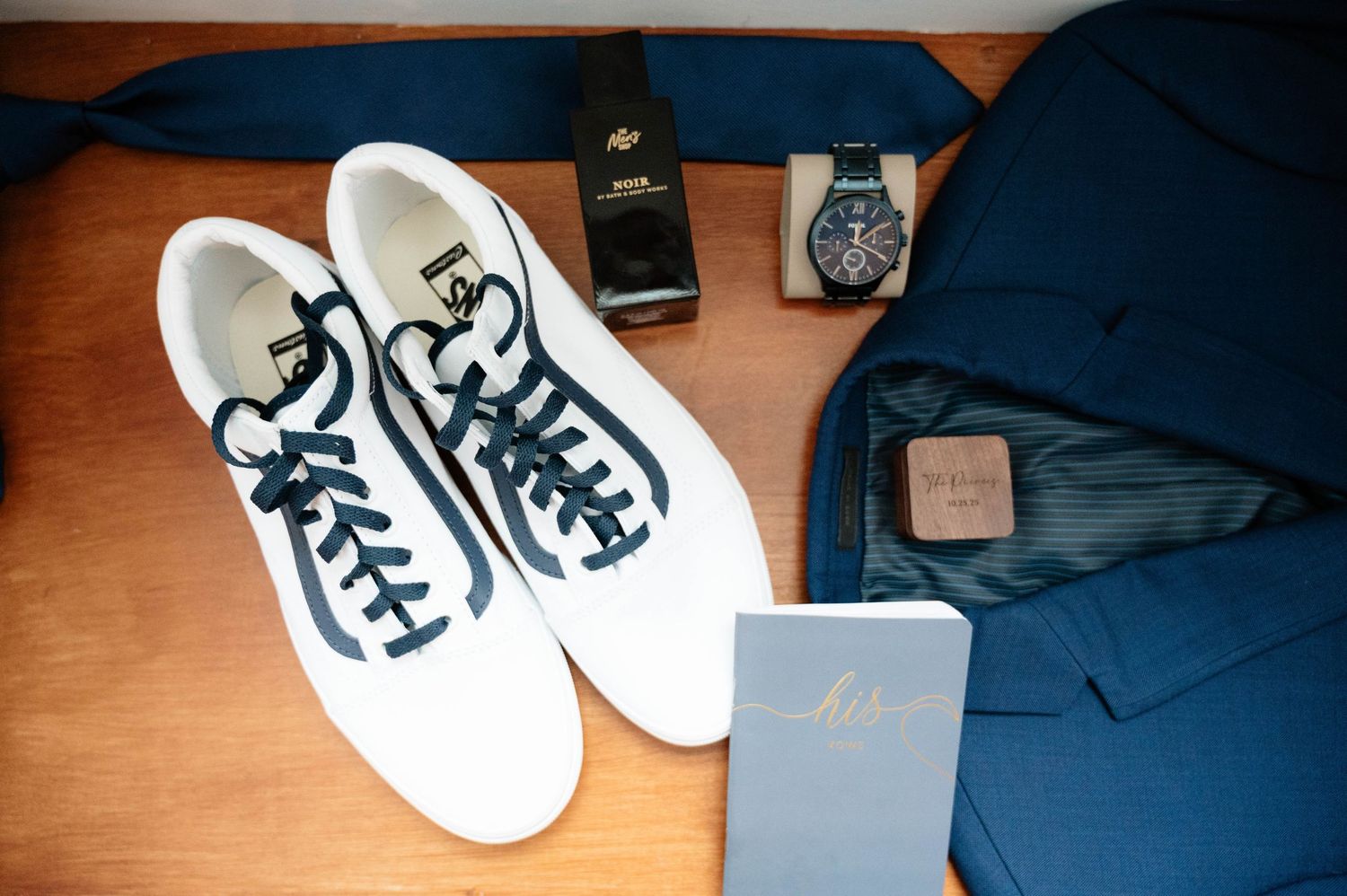 Formal dress shoes and watches arranged on wooden surface for wedding preparation.