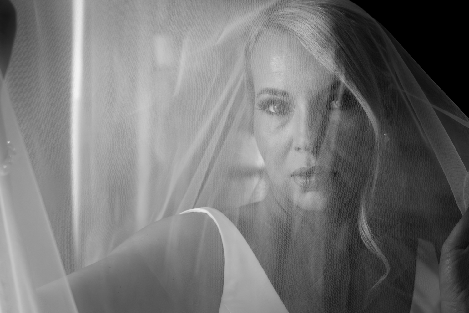 Black and white bridal portrait of blonde woman wearing wedding veil, elegant and ethereal photography.