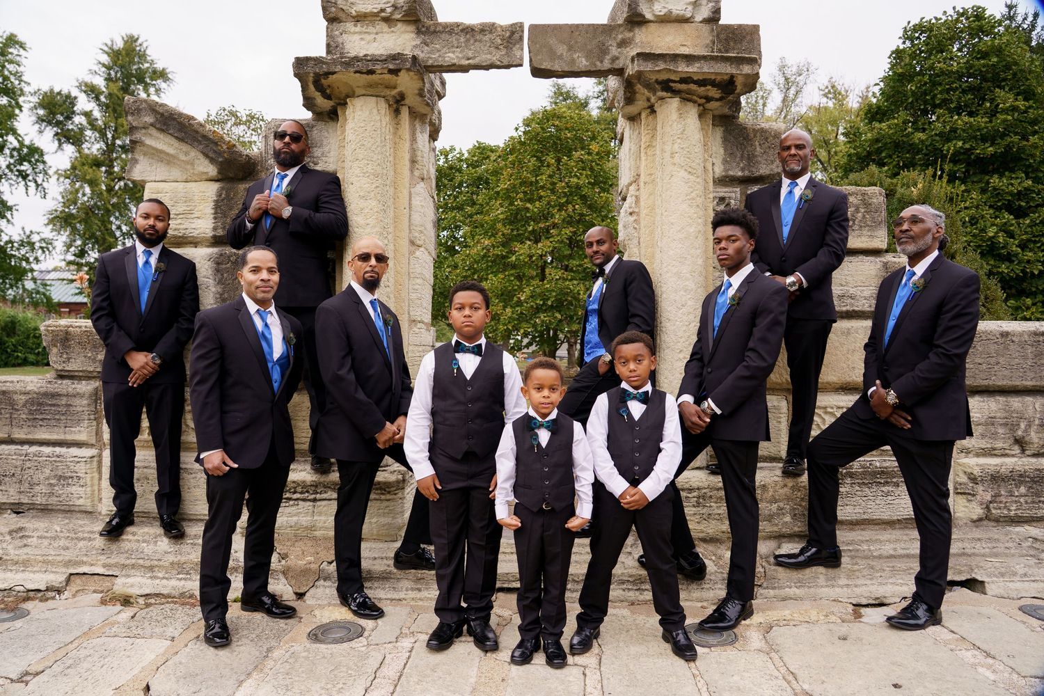 Wedding party in formal attire posed on stone steps outdoors.